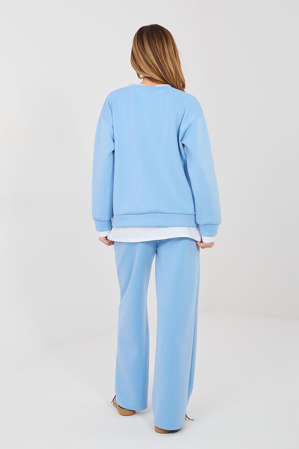 Person wearing a light blue sweatshirt and pants on a white background