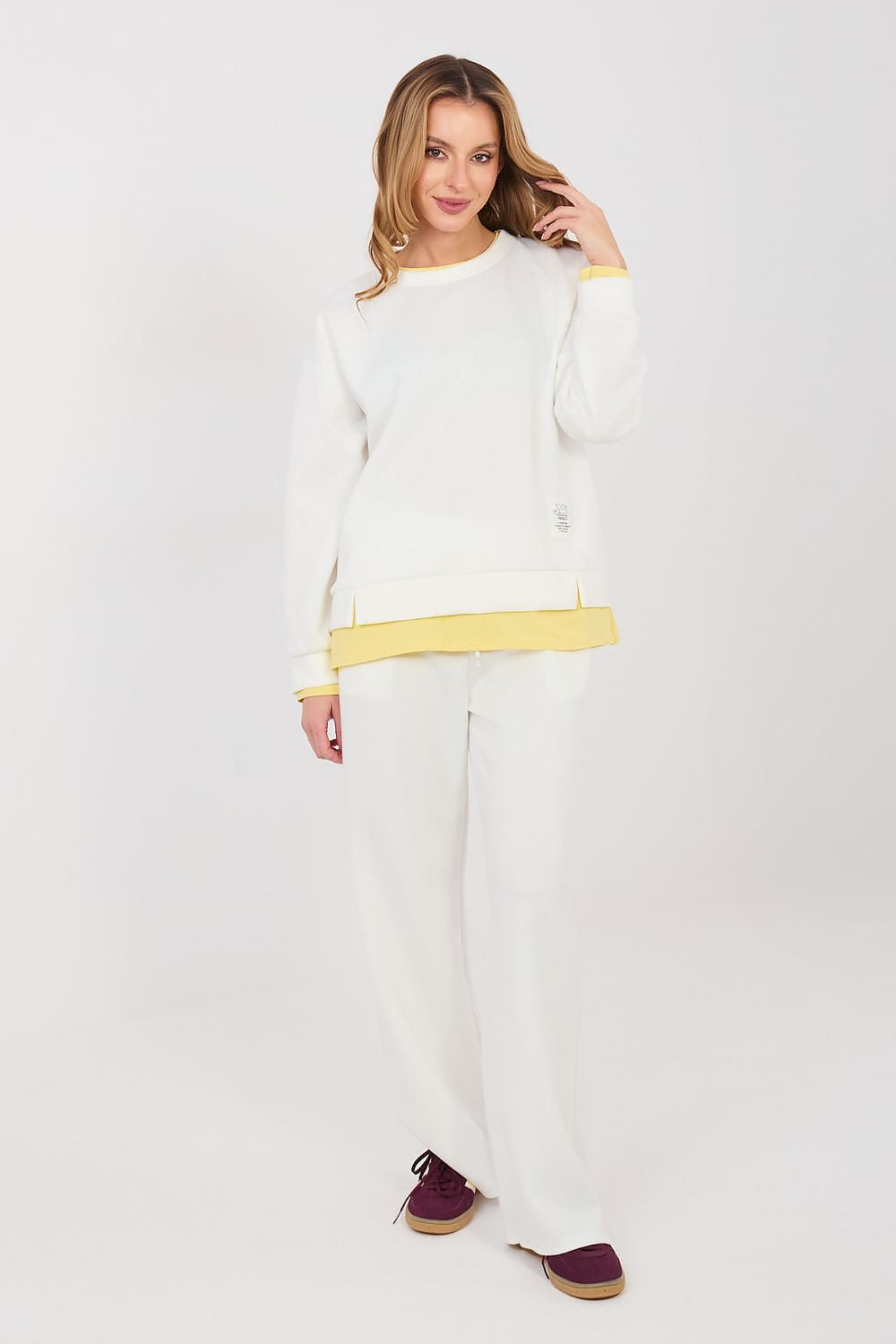 Woman wearing a white outfit with yellow accents on a plain background