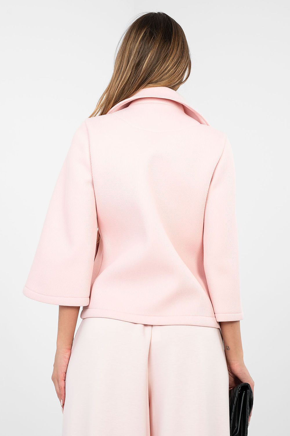 Person wearing a light pink blazer and pants on a white background