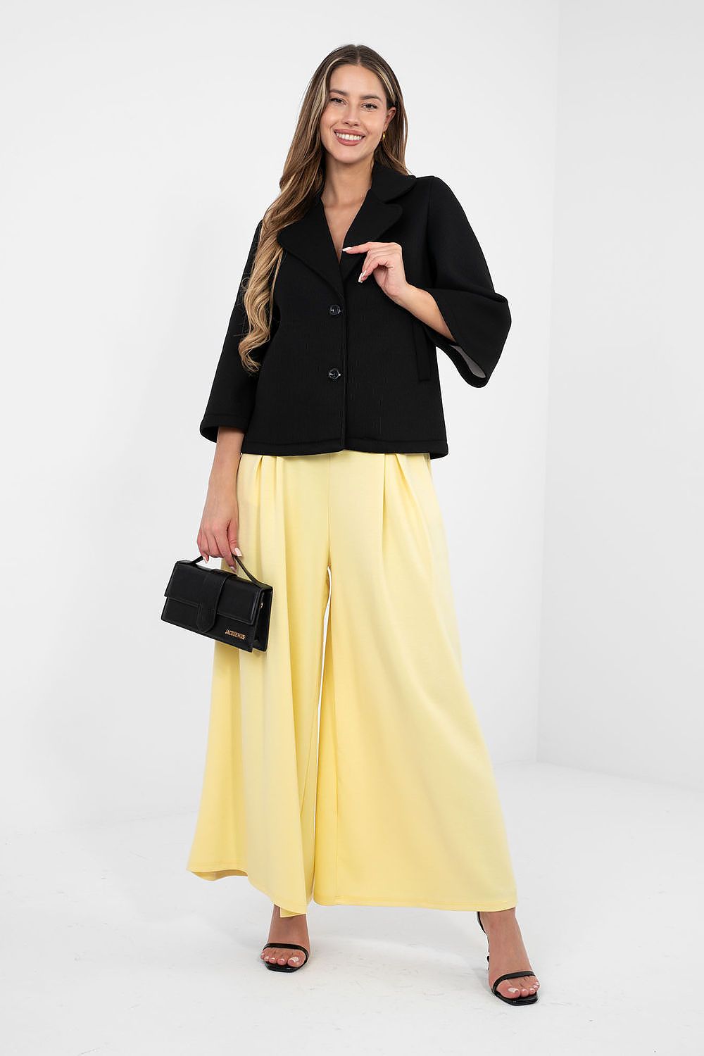 Woman wearing a black jacket and yellow pants on a white background