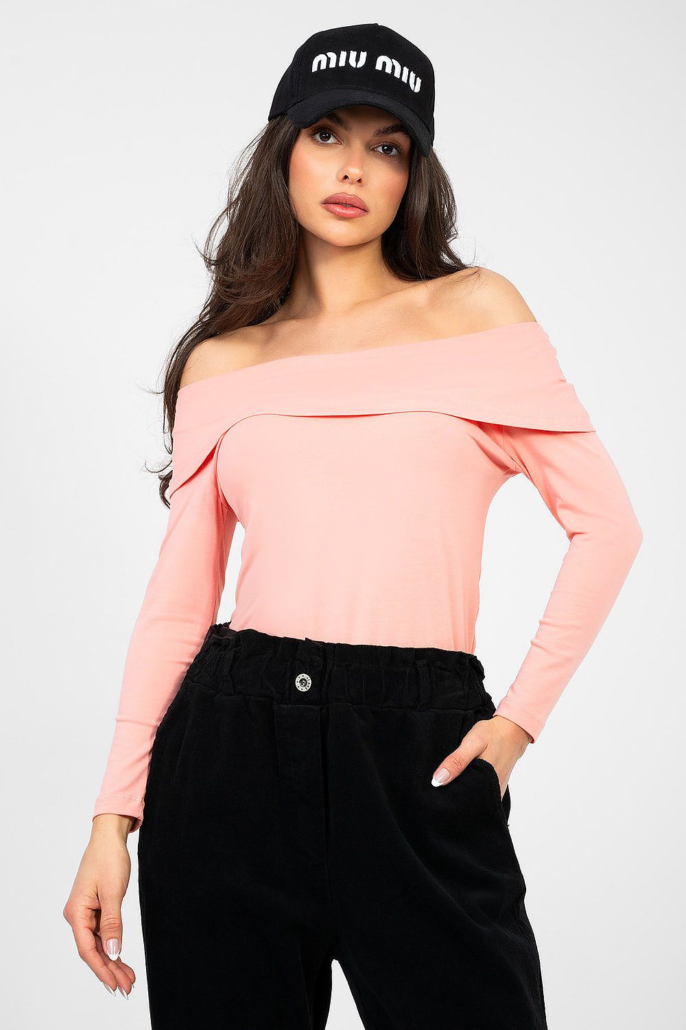 Woman wearing a pink off-shoulder top and black cap with 'MIU MIU' branding on a white background