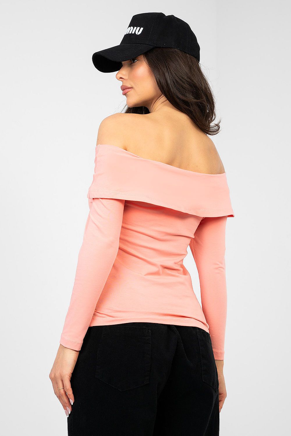 Woman wearing a pink off-shoulder top and black cap on a white background