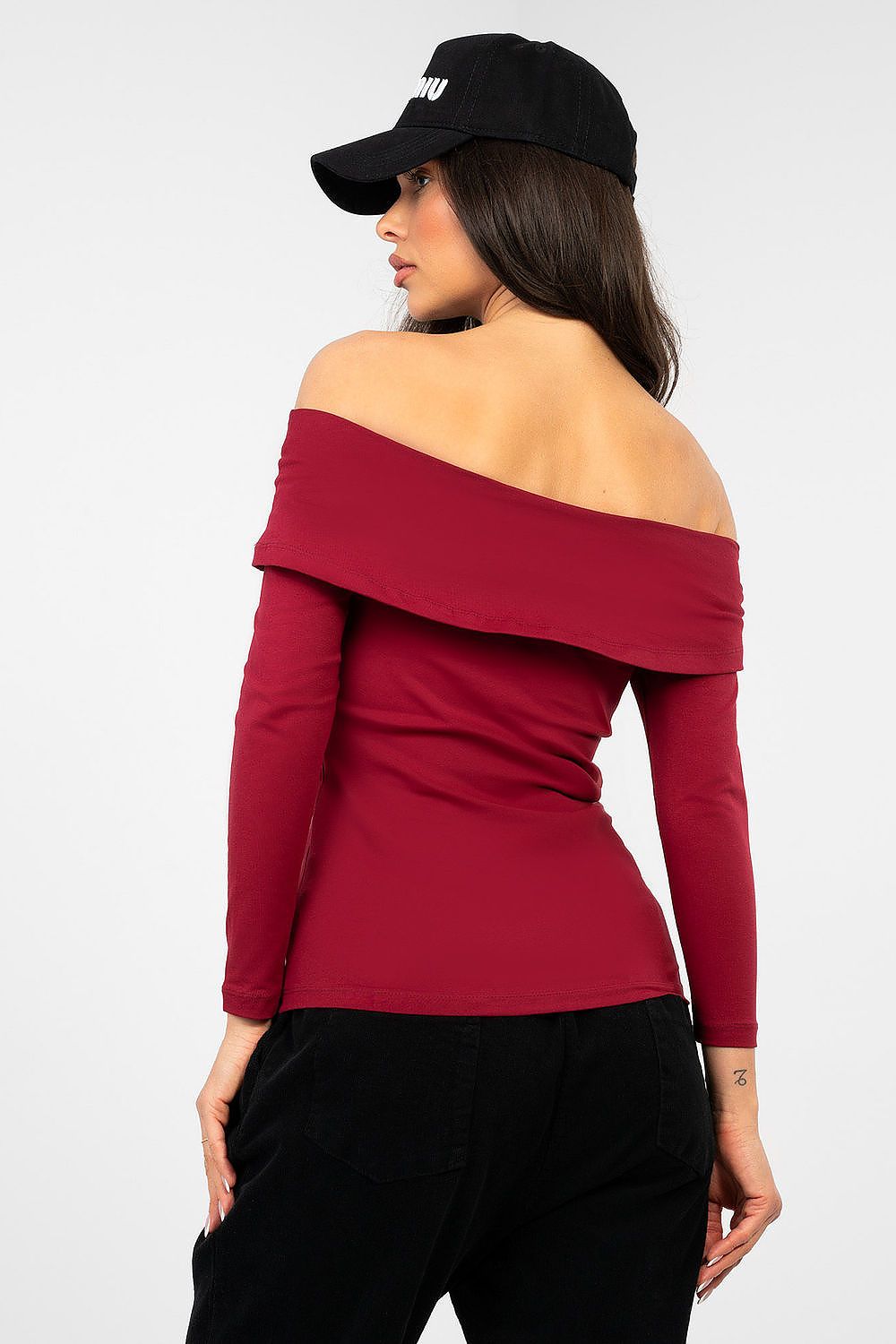 Woman wearing a red off-shoulder top and black cap on a white background