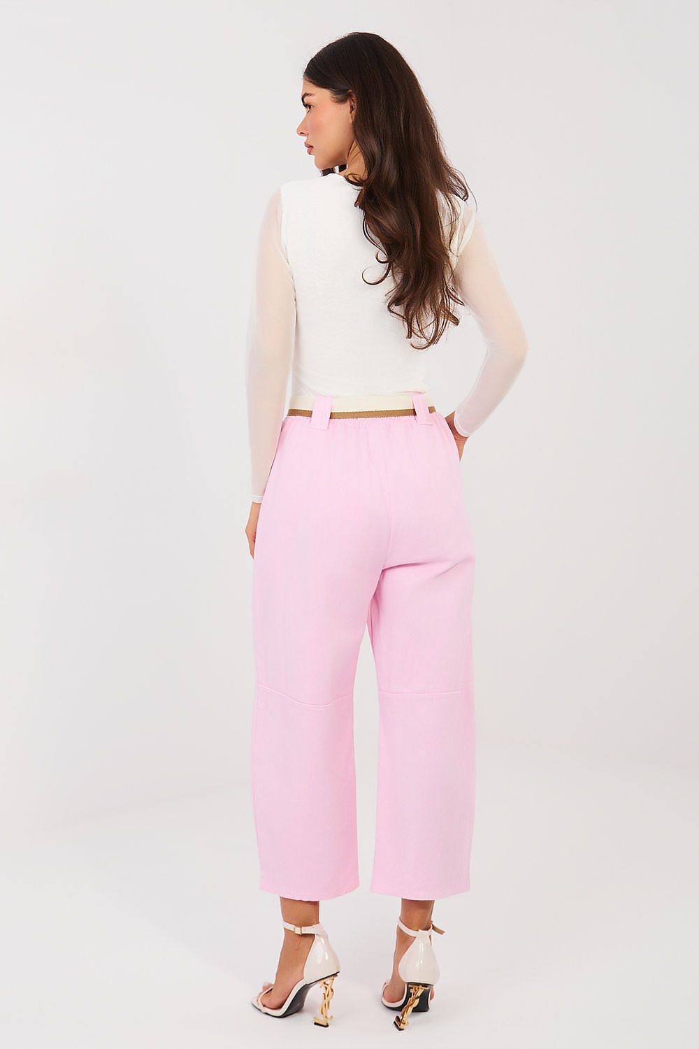 Woman wearing a white top and pink pants on a white background