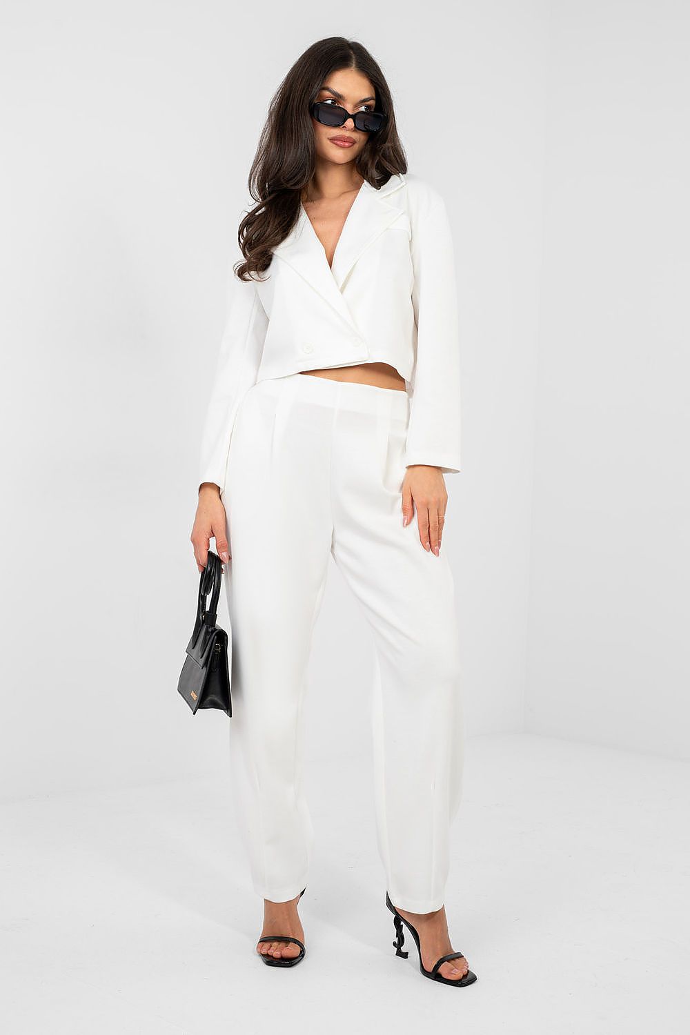 Woman wearing a white outfit with black accessories on a white background