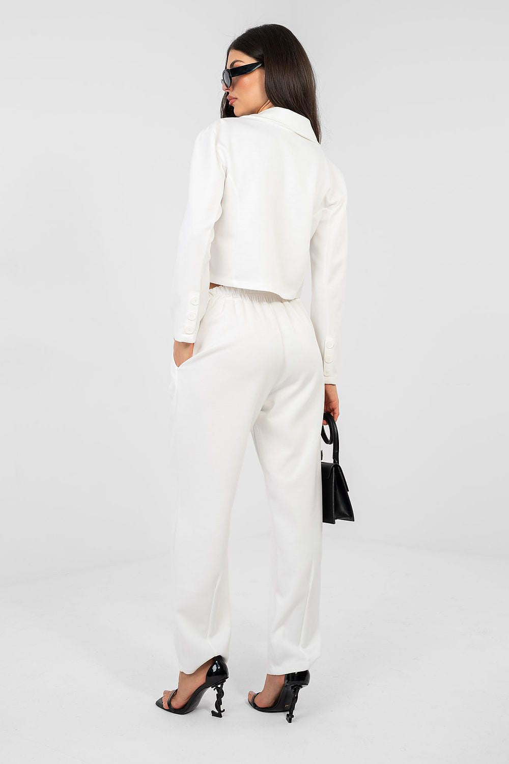 Woman wearing a white outfit with black high heels on a white background