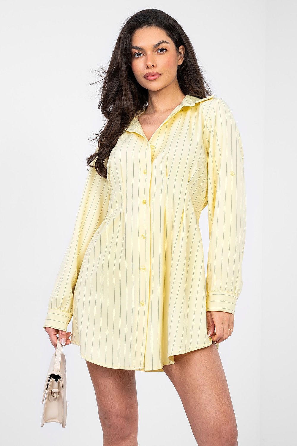 Woman wearing a light yellow button-up dress against a white background
