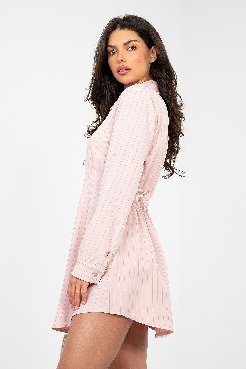 Woman wearing a light pink ribbed shirt dress on a white background