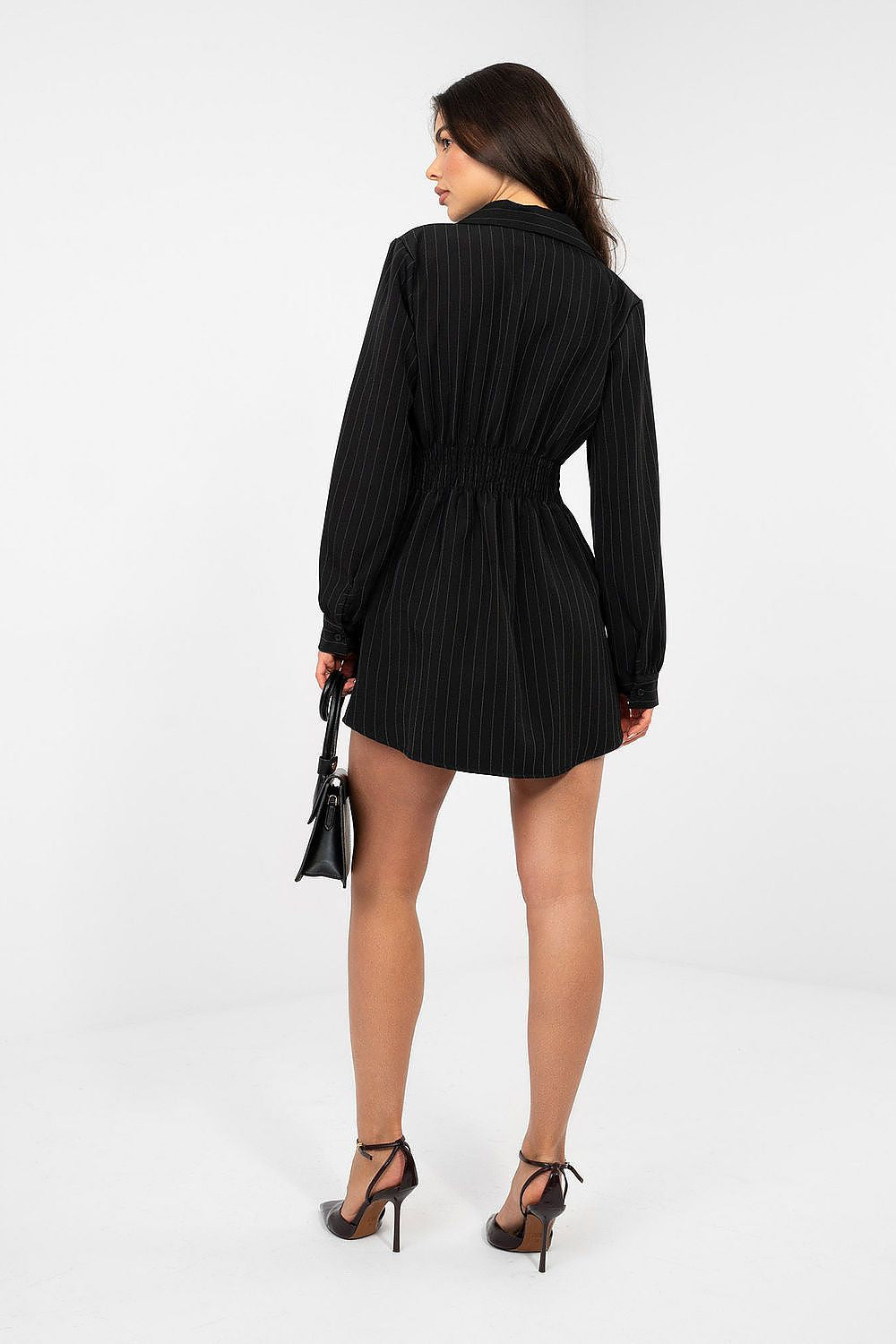 Woman wearing a black dress with long sleeves on a white background