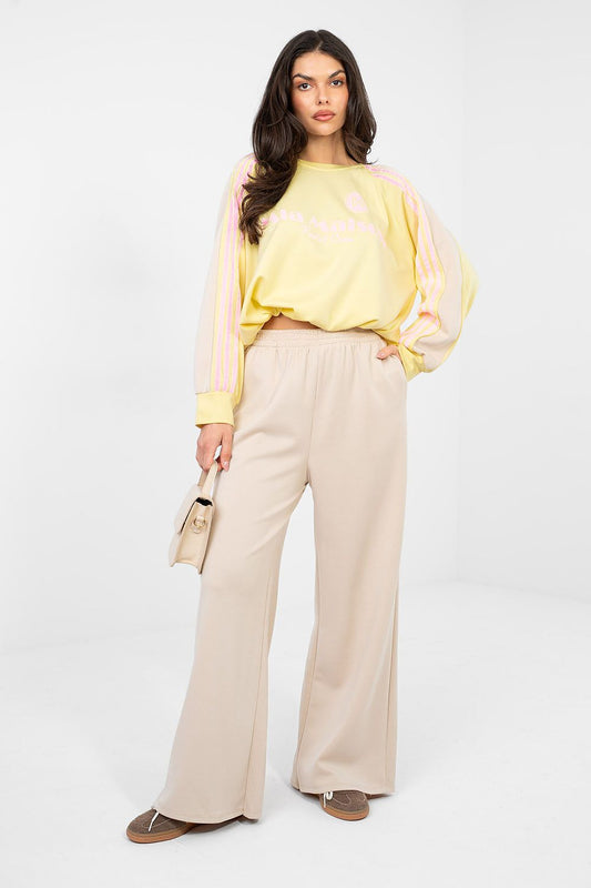 Woman wearing a yellow top and beige pants on a white background