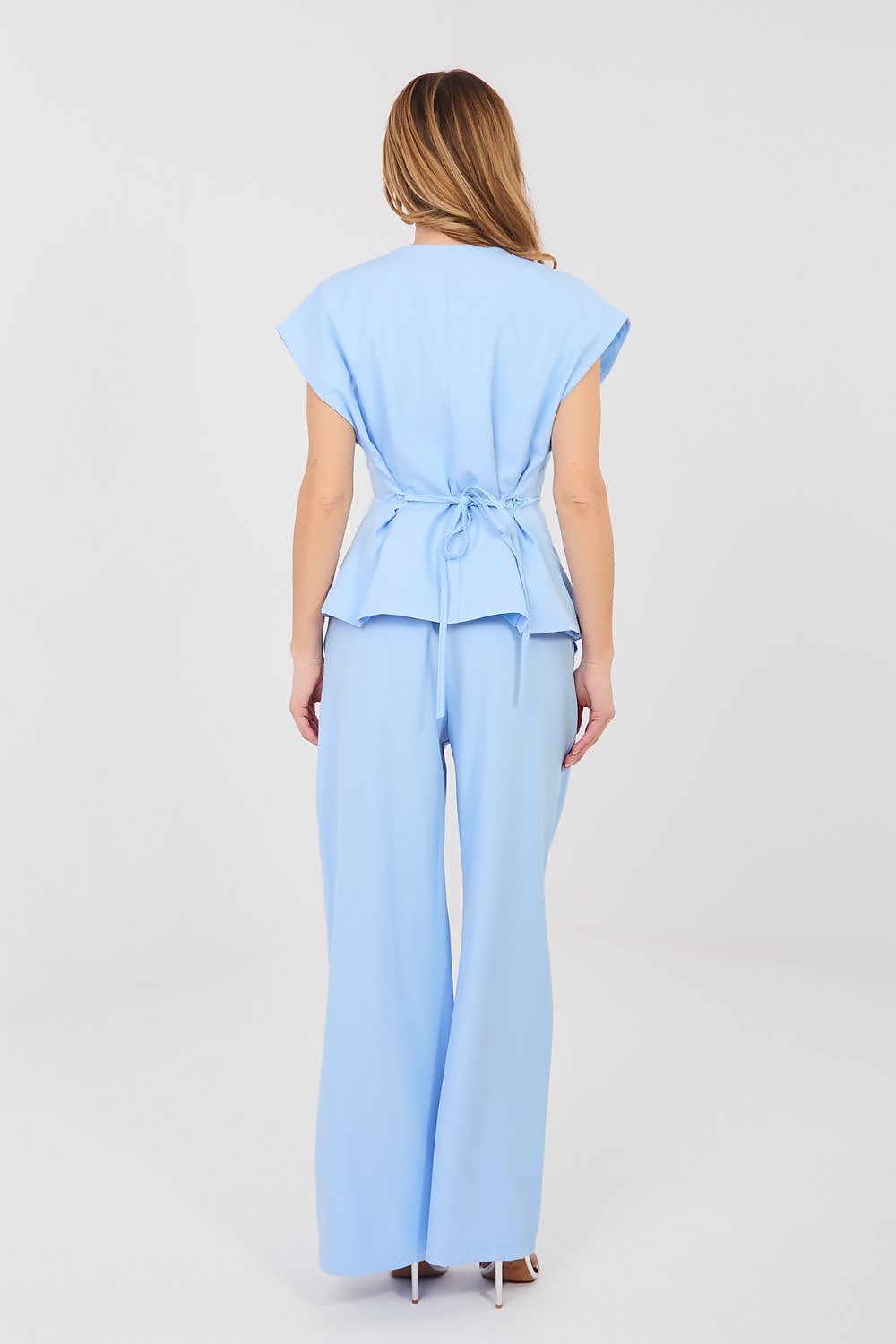 Woman wearing a light blue outfit with a top and wide-leg pants on a white background