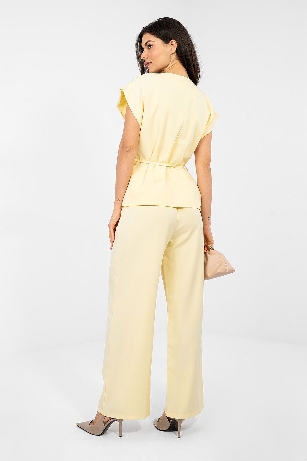 Woman wearing a yellow jumpsuit on a white background