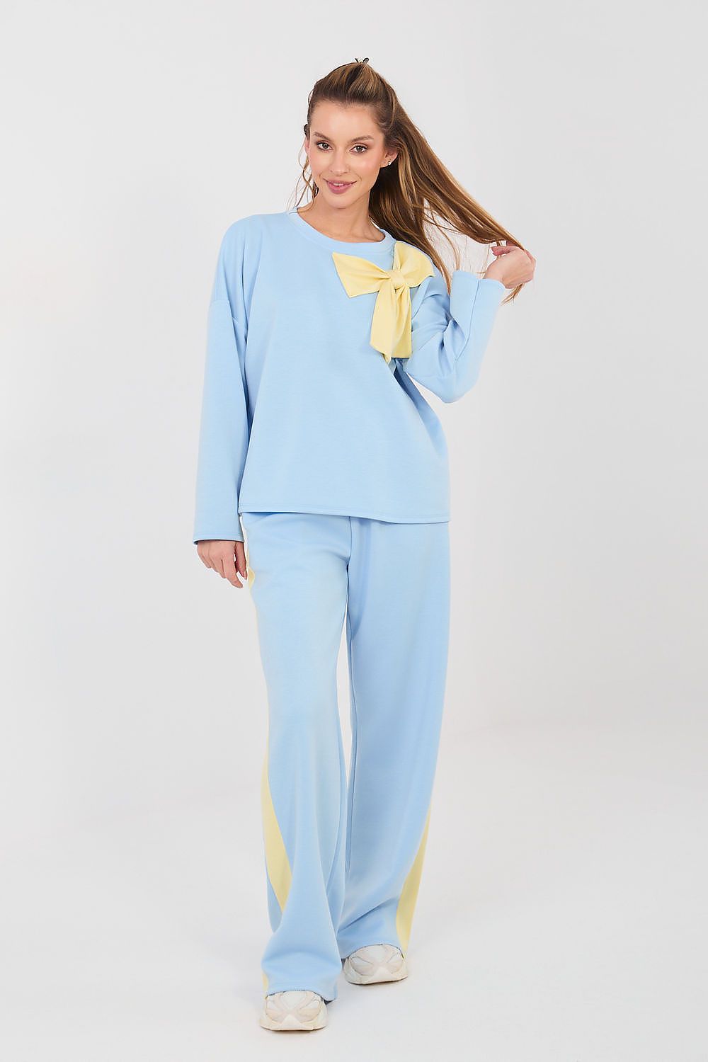 Woman wearing a light blue pajama set with a yellow bow on a white background