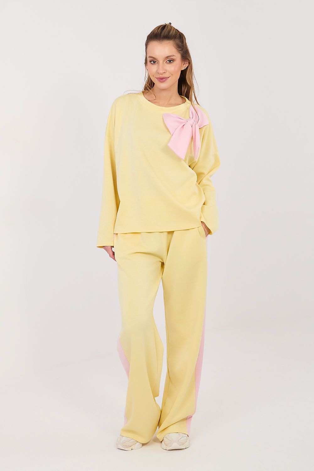 Woman wearing a yellow outfit with a pink bow on a white background