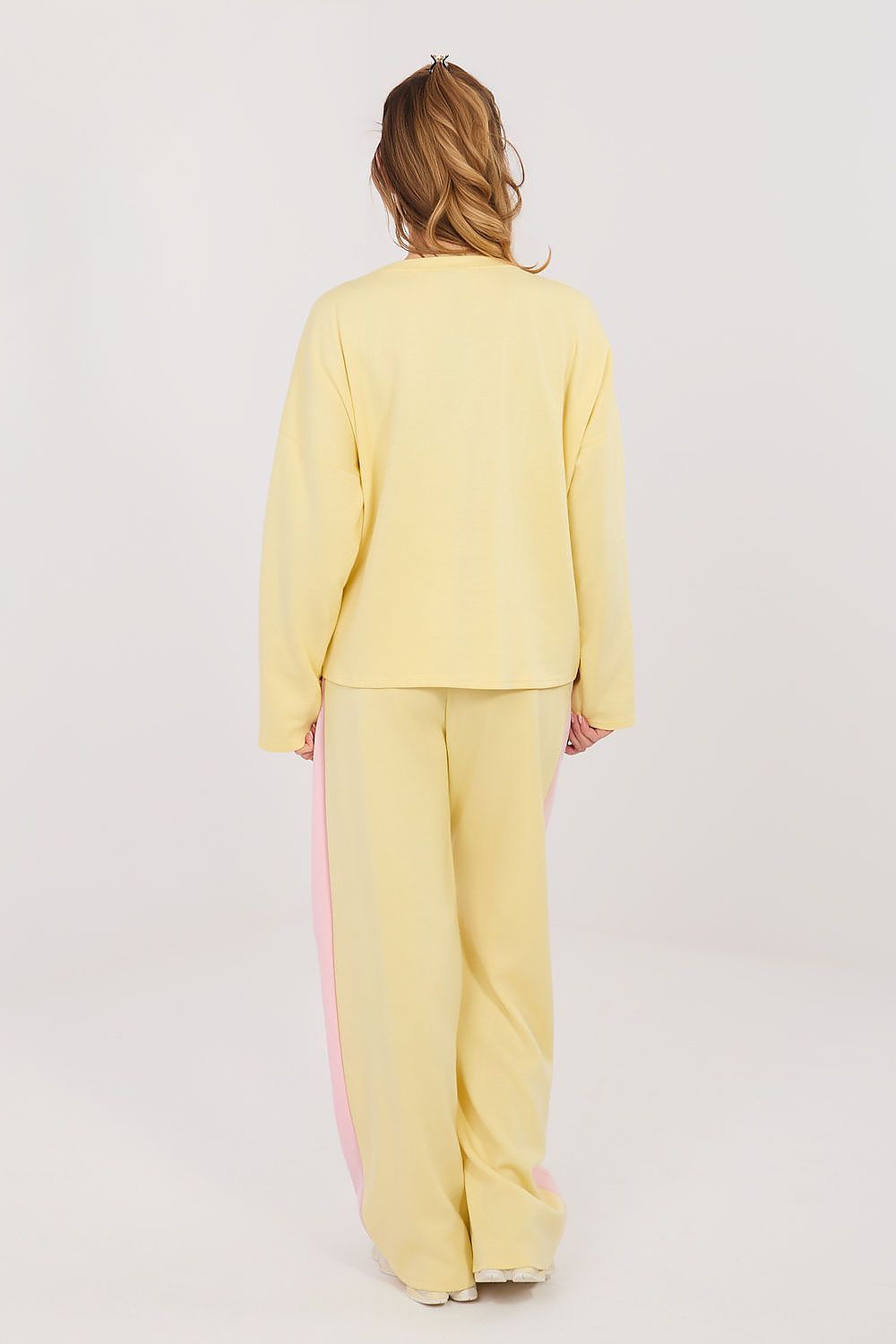 Person wearing a yellow outfit with pink stripes on a white background