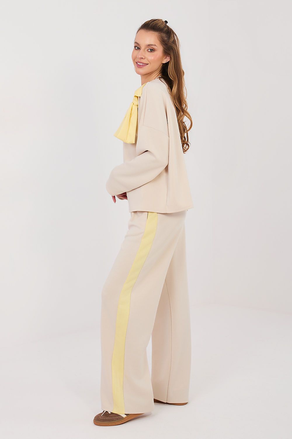 Woman wearing a beige outfit with yellow accents on a white background