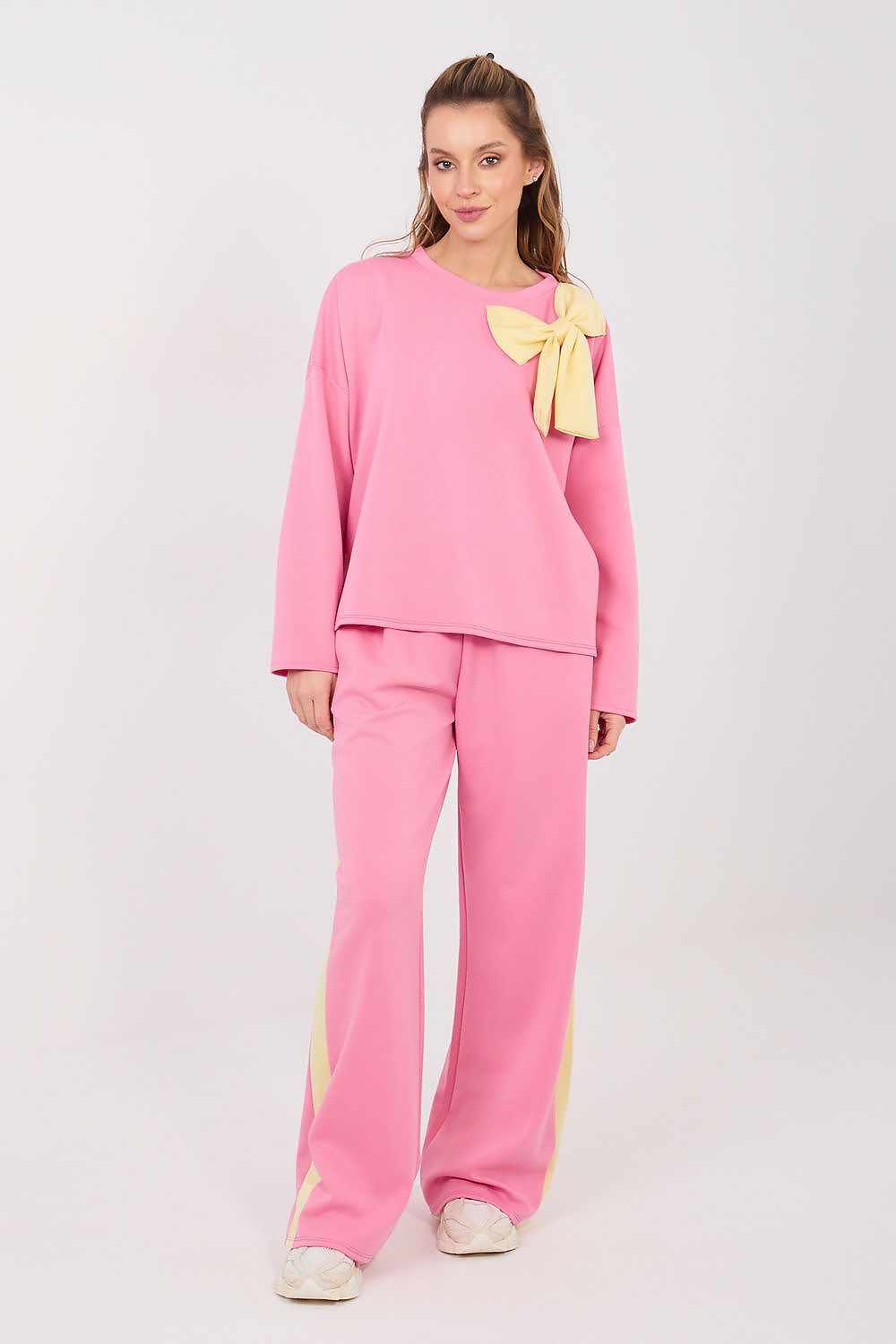 Woman wearing a pink outfit with a yellow bow on a white background