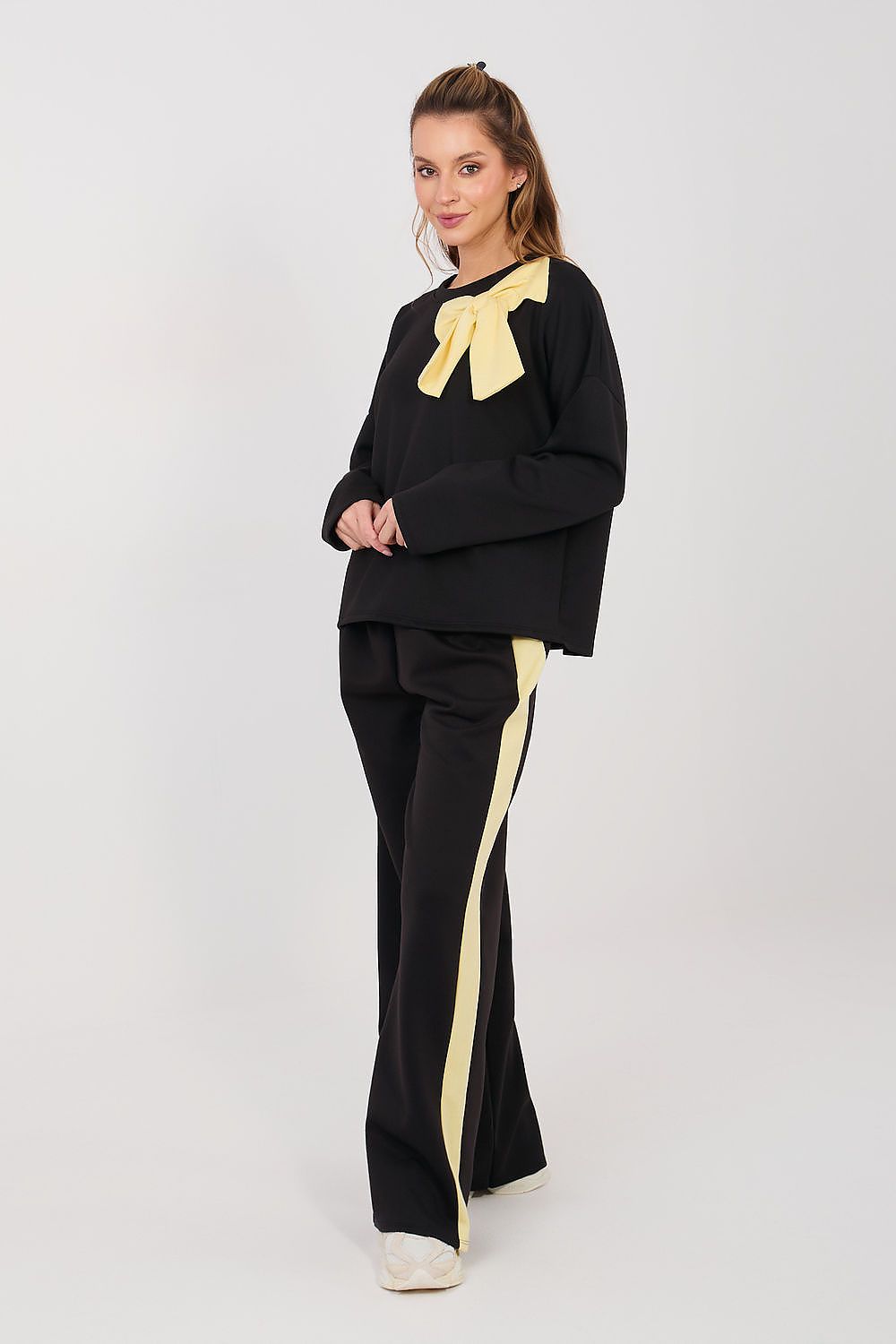 Woman wearing a black outfit with yellow accents on a white background