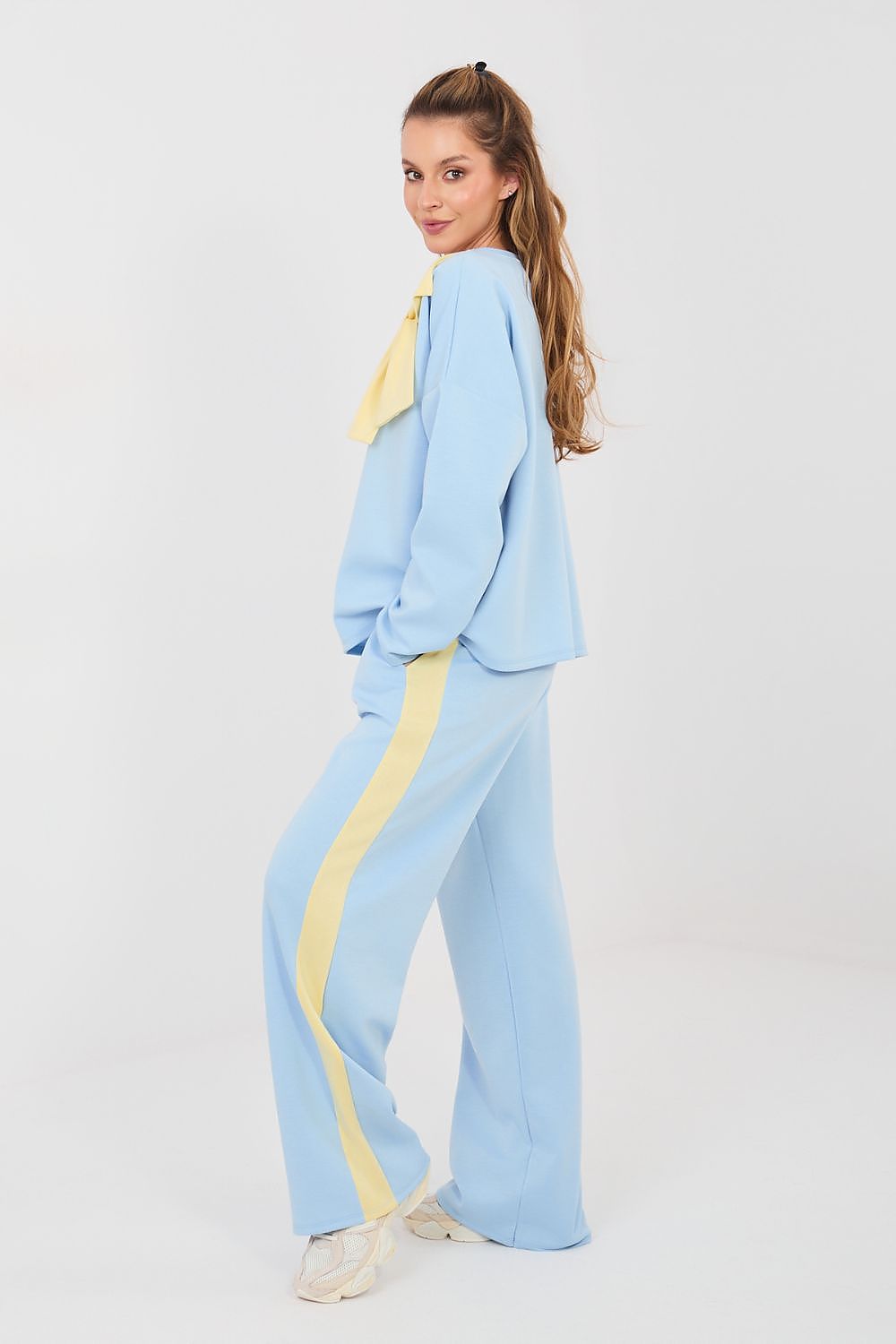 Woman wearing a light blue outfit with yellow accents on a white background