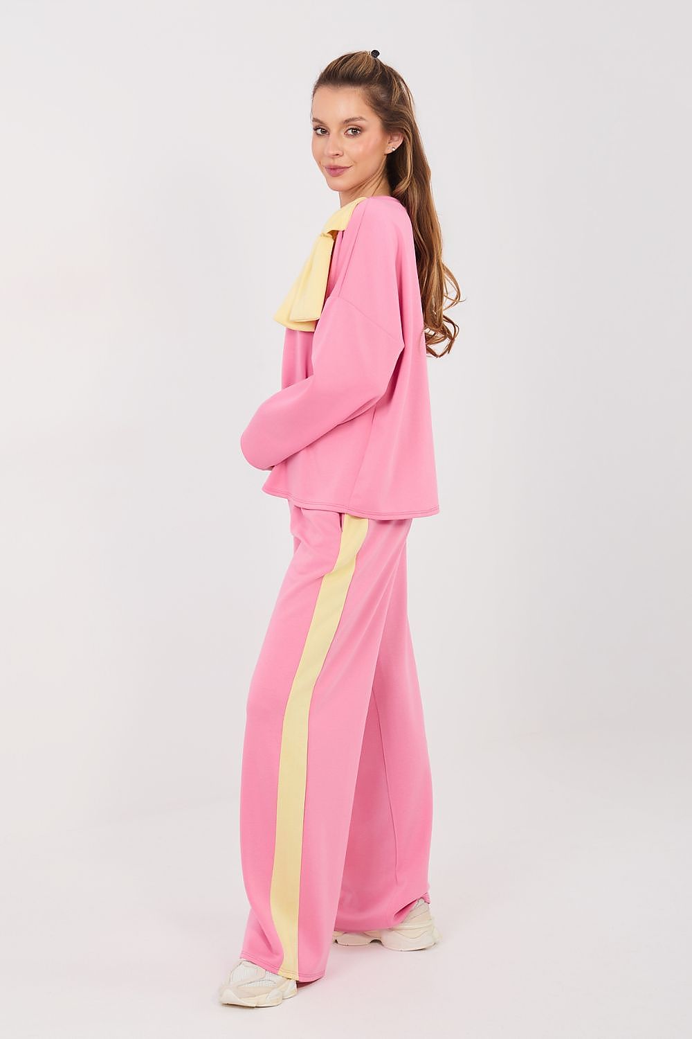 Person wearing a pink tracksuit with yellow accents on a white background