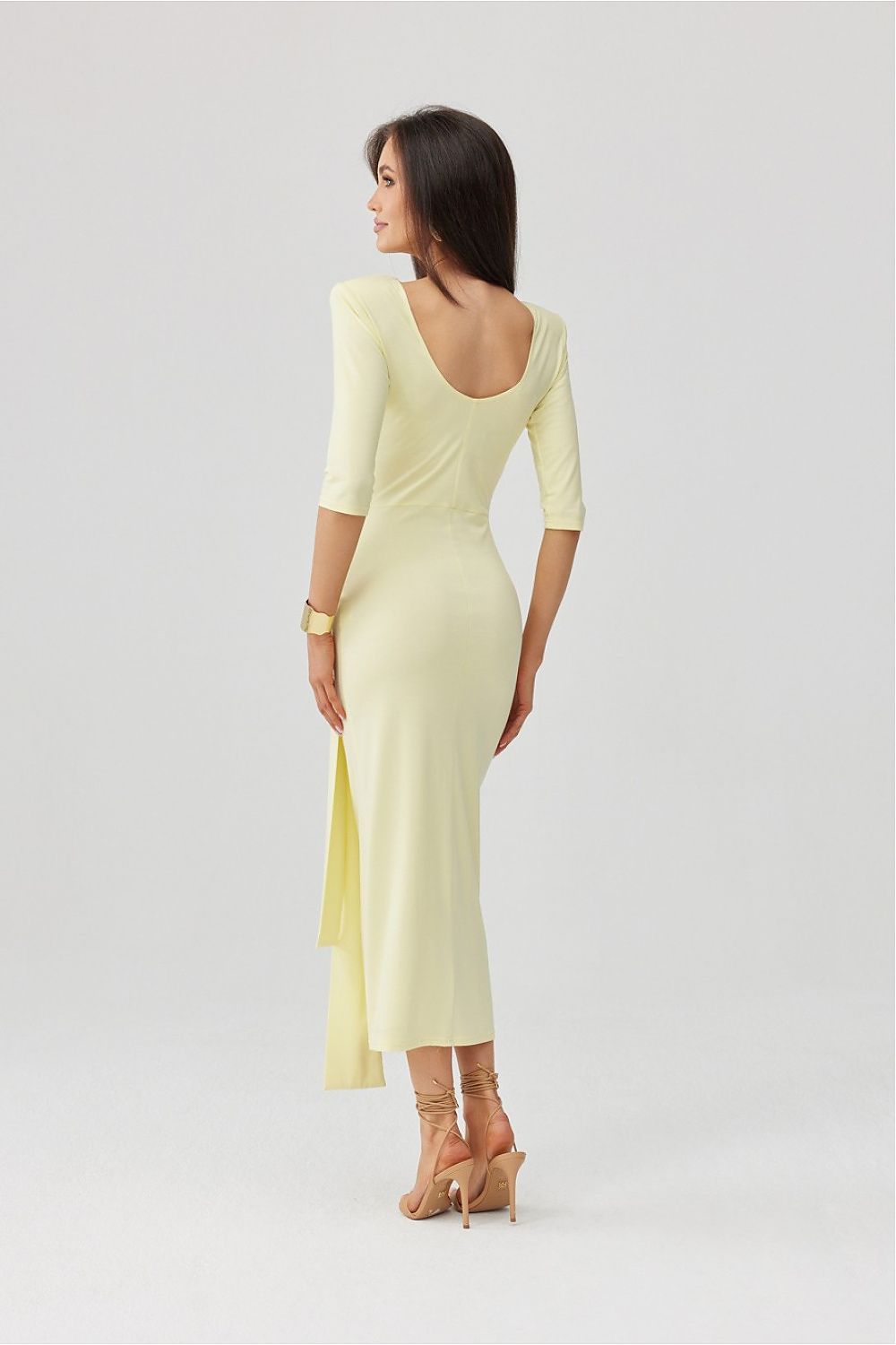 Woman wearing a light yellow dress with a slit on a white background