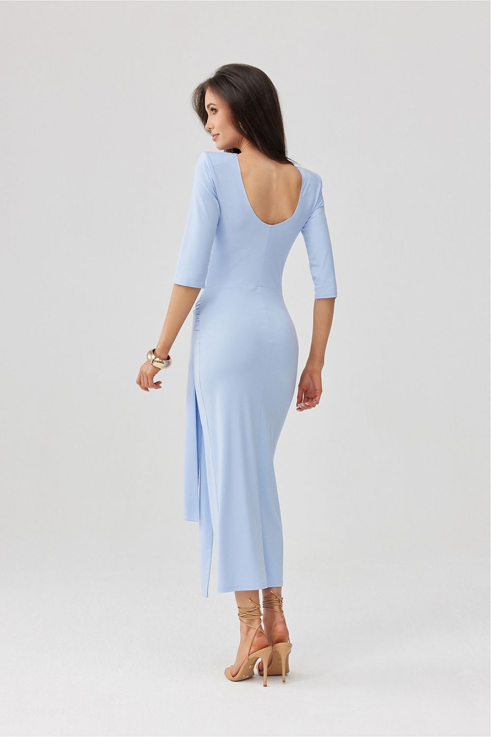 Woman wearing a light blue dress with a slit on a white background