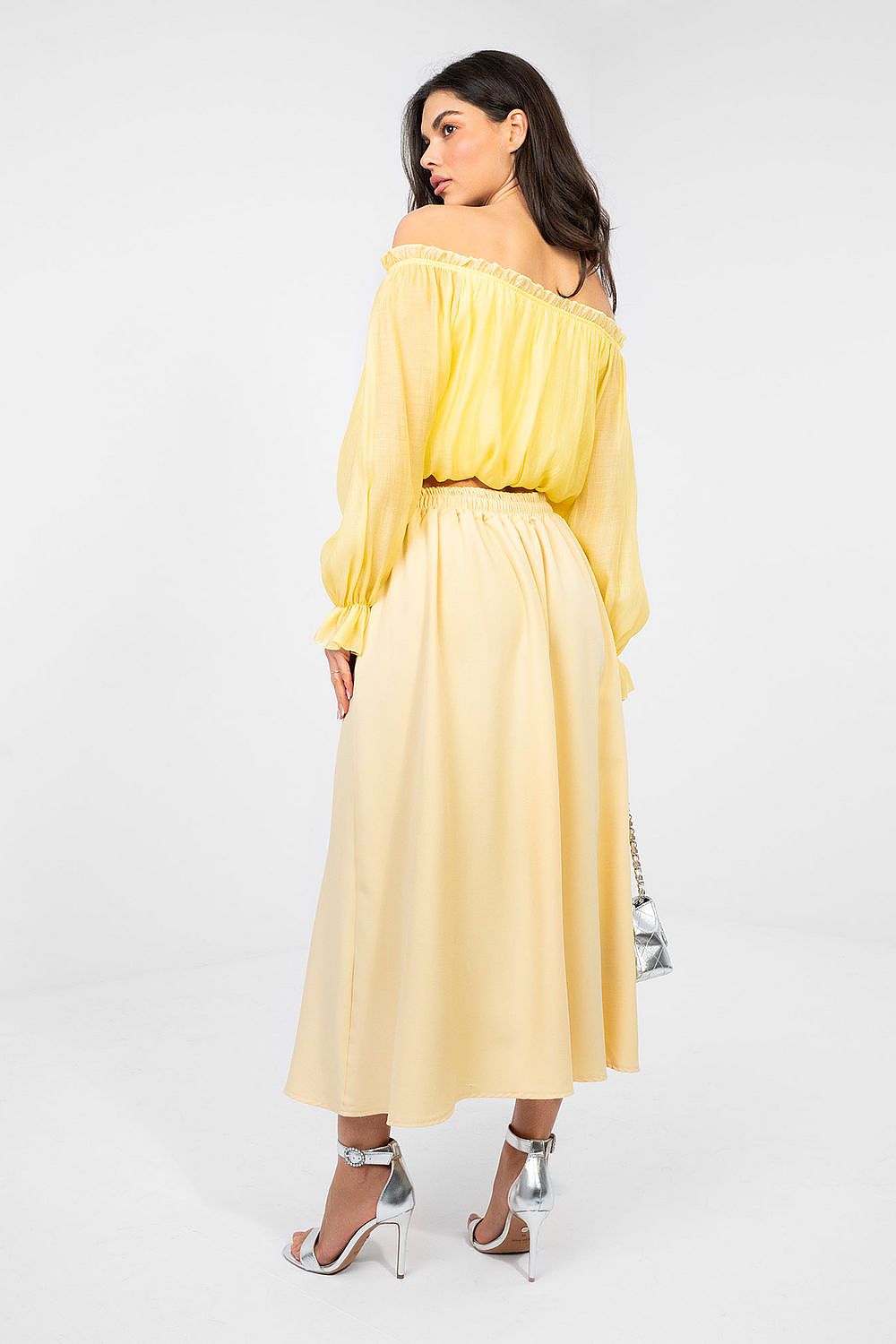 Woman wearing a yellow off-shoulder dress on a white background