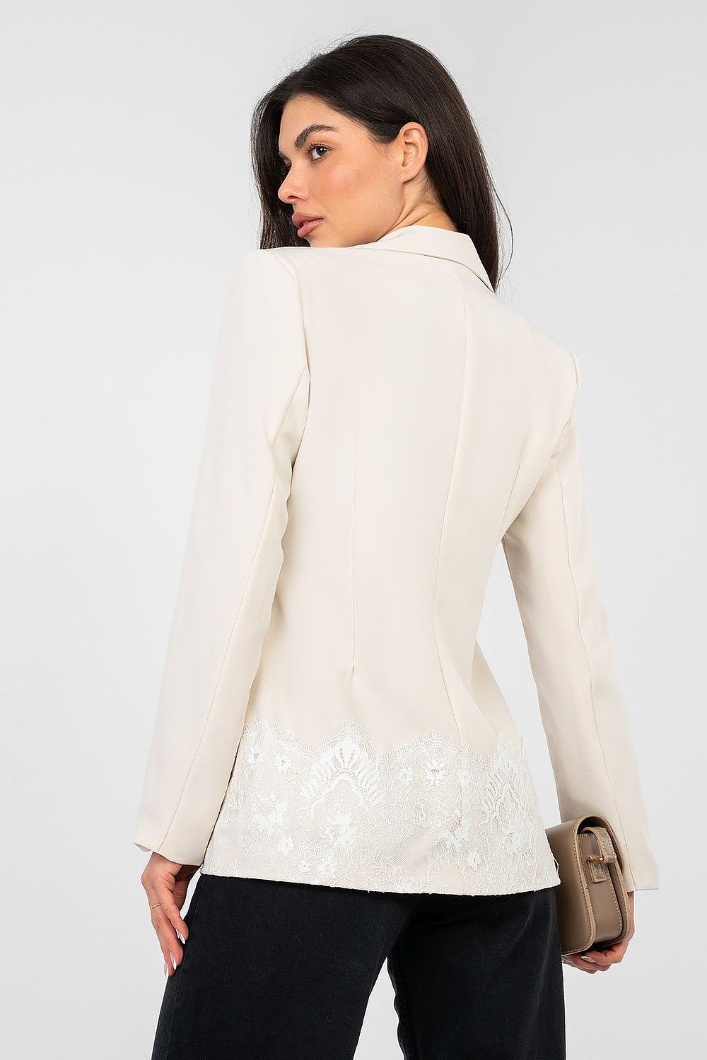 Woman wearing a cream blazer with floral details on a white background