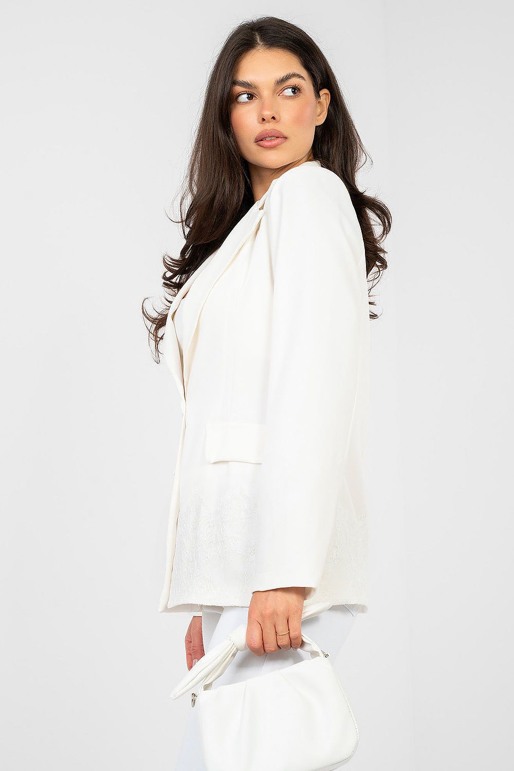 Woman wearing a white blazer against a plain background
