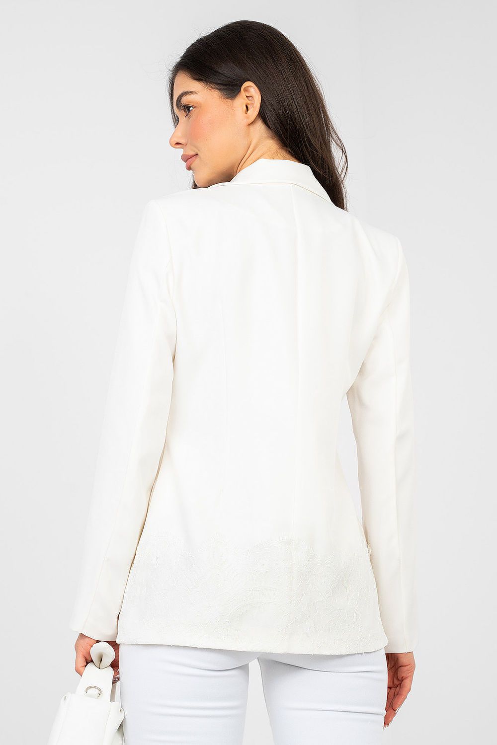 Woman wearing a white blazer against a plain background
