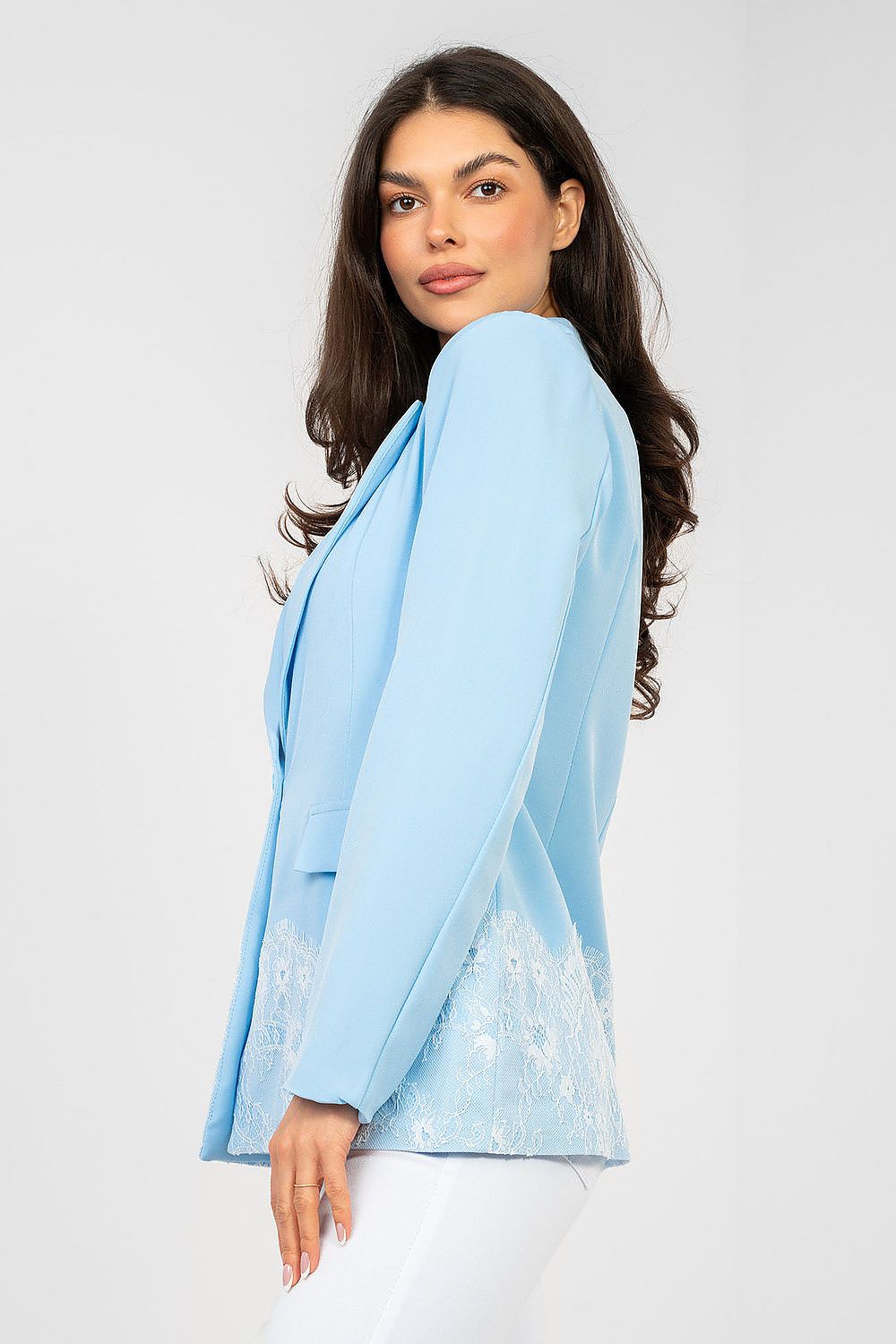 Woman wearing a light blue blazer over a white top on a plain background