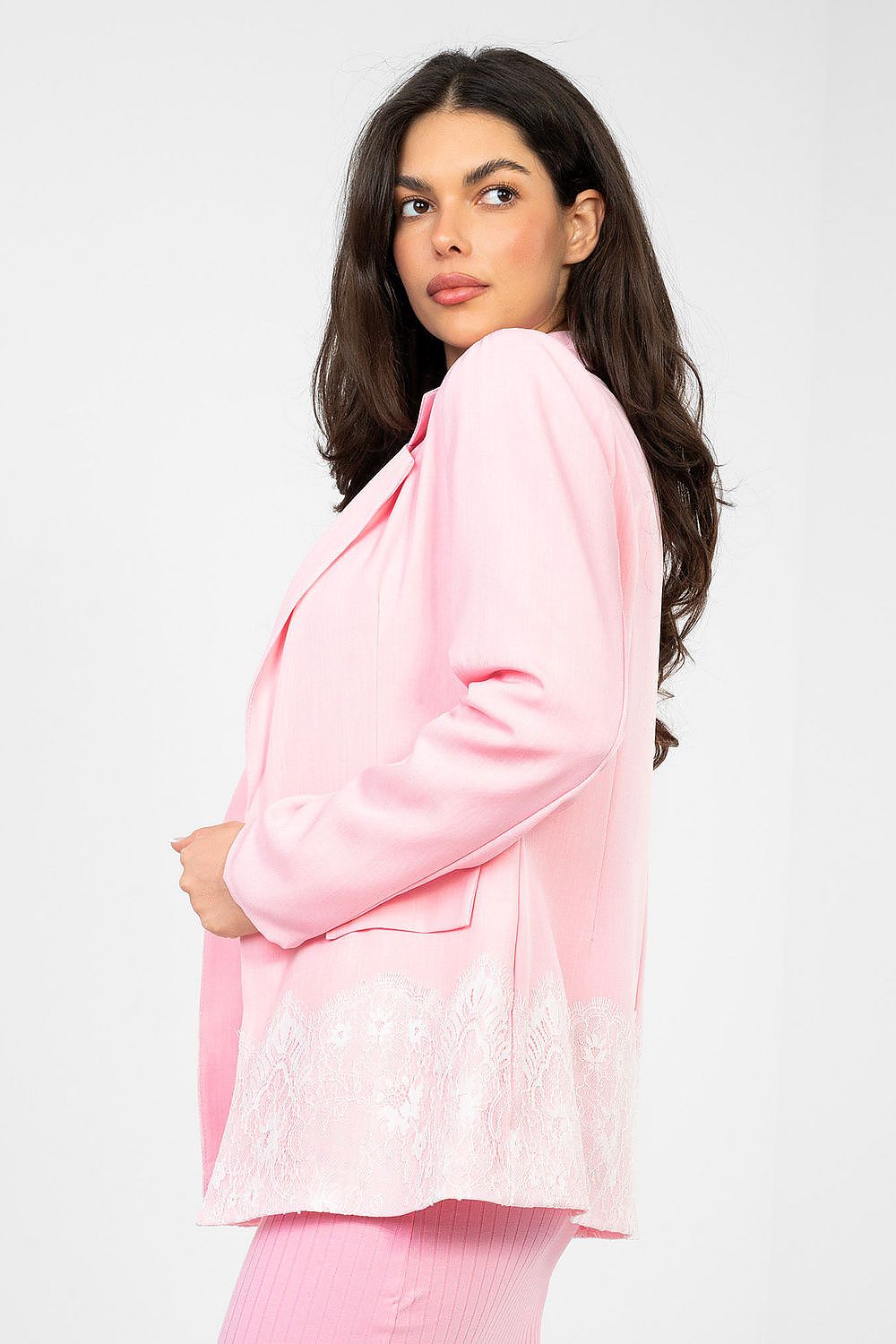 Woman wearing a pink outfit with lace details on a white background
