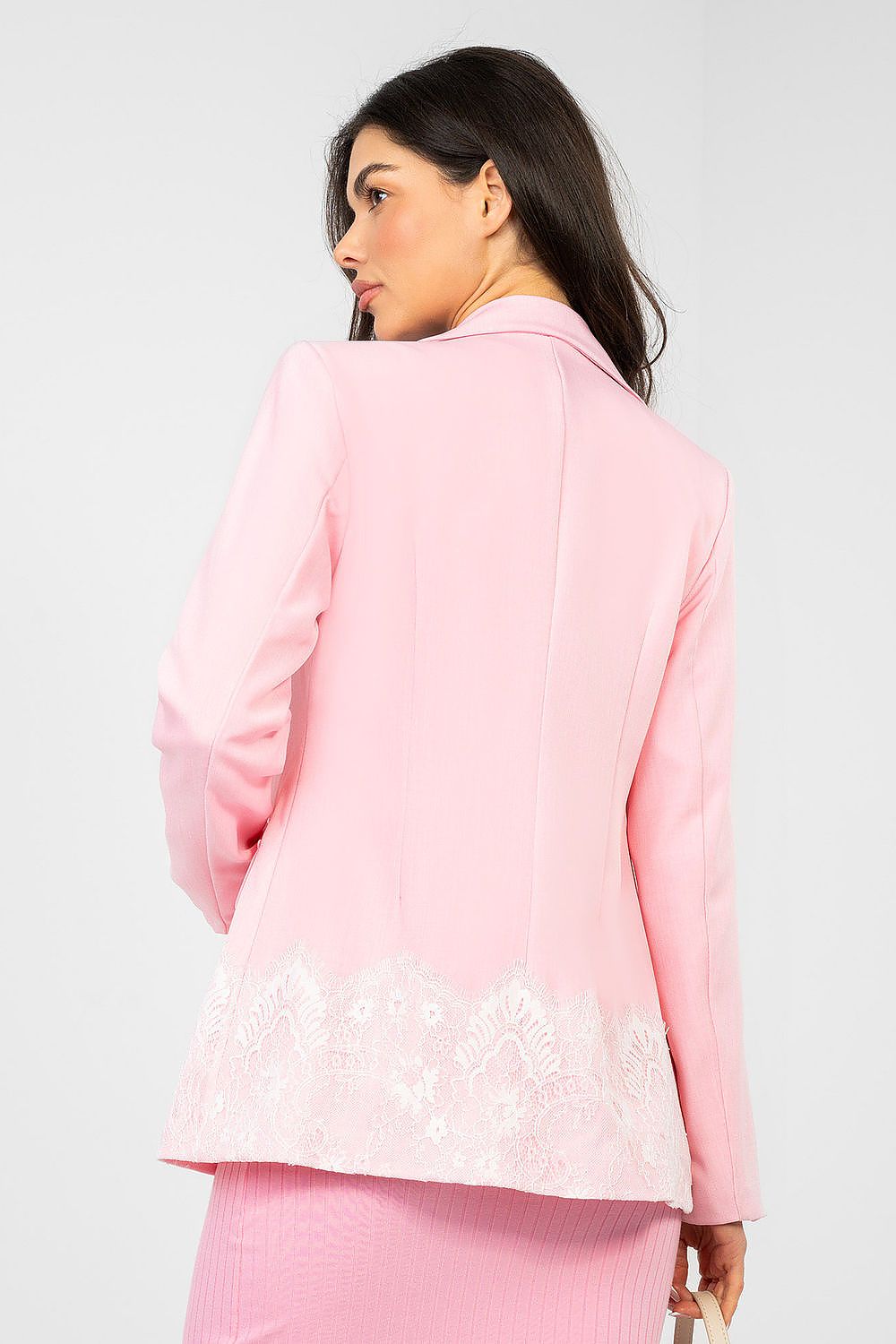 Woman wearing a pink outfit with lace details on a white background