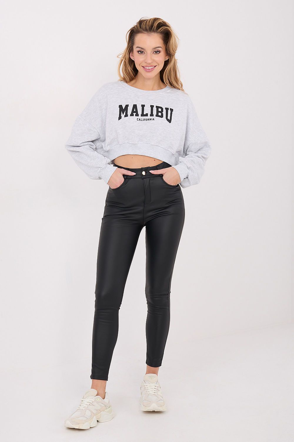 Woman wearing a gray 'Malibu' sweatshirt and black pants on a white background