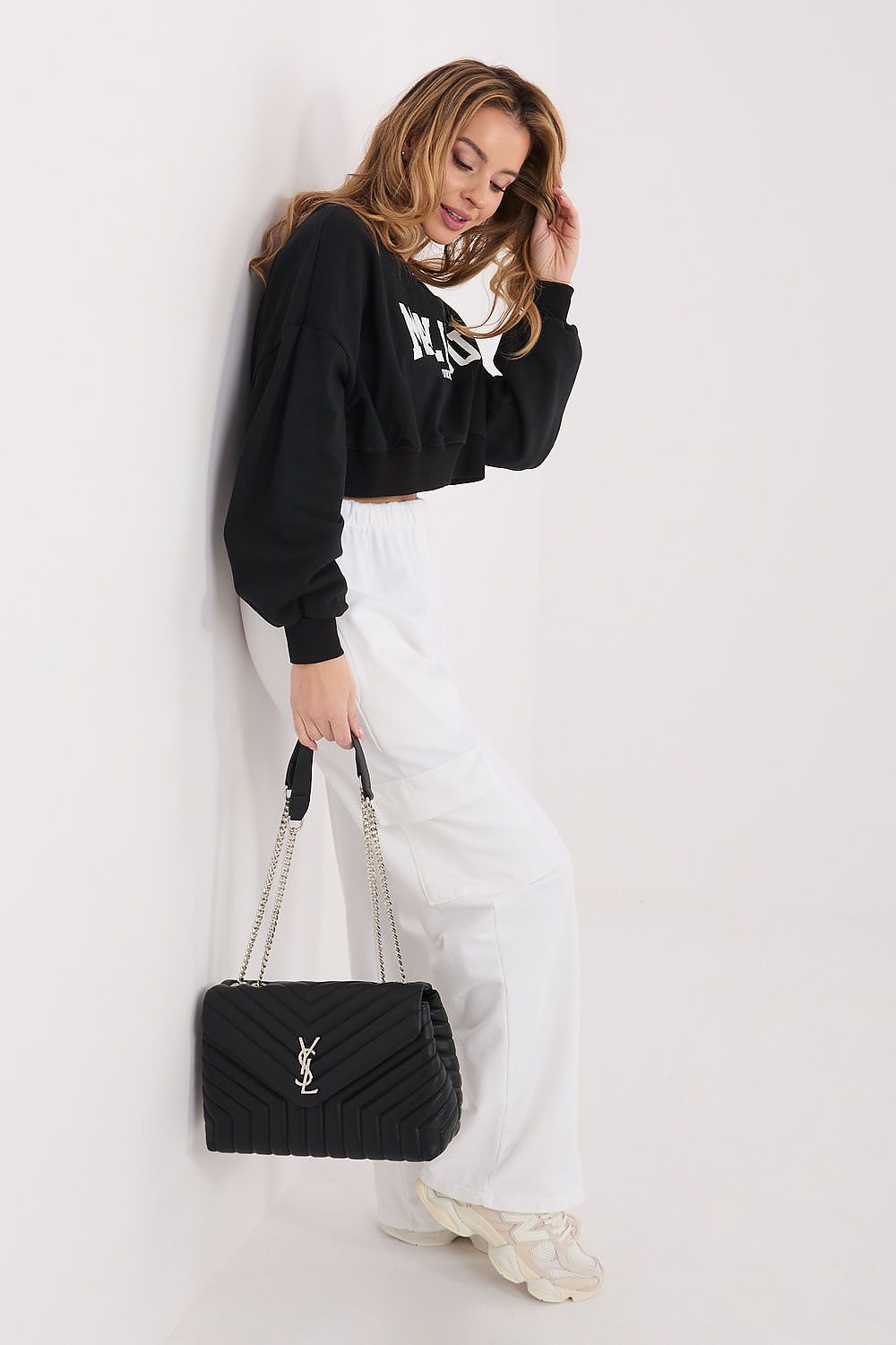 Woman holding a black handbag against a white background
