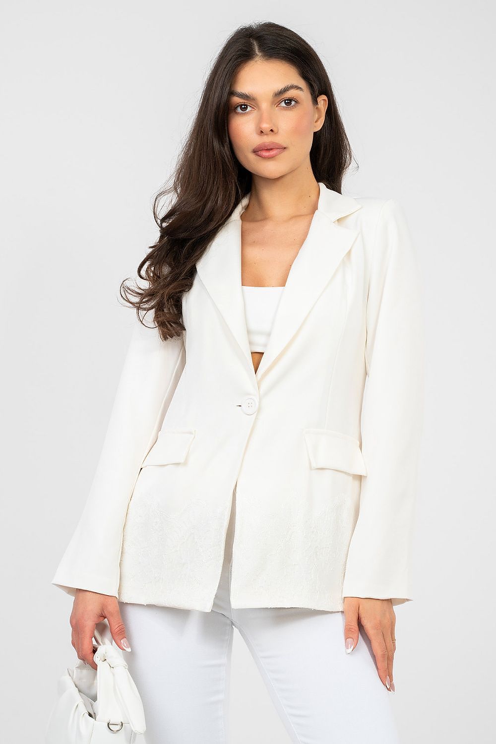 Woman wearing a white blazer and pants against a plain background