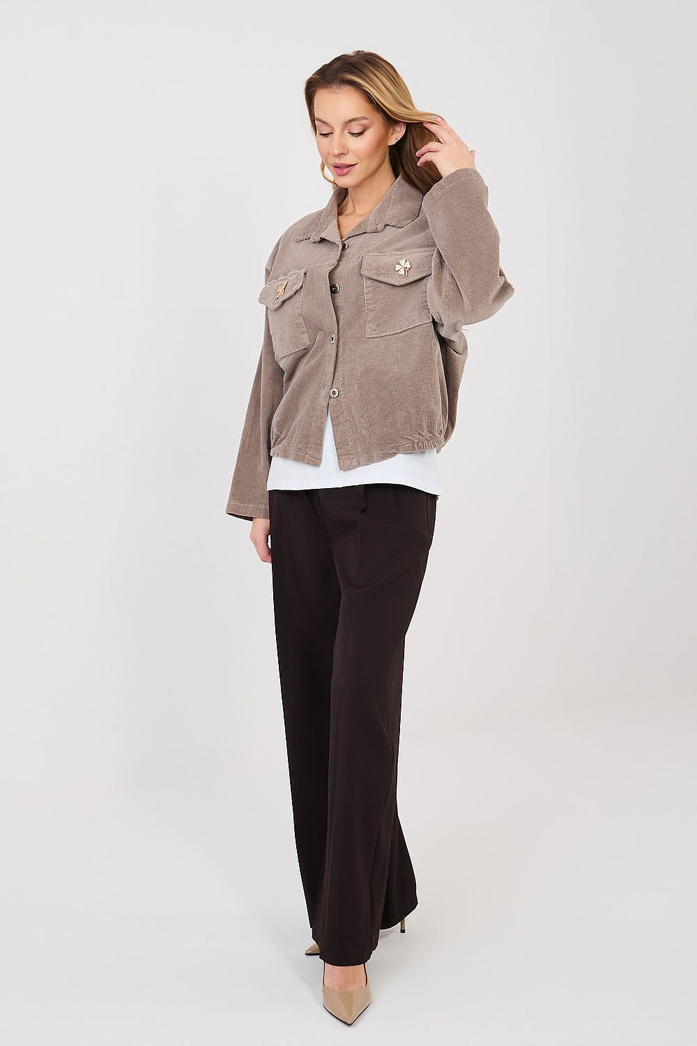 Woman wearing a brown jacket and black pants on a white background