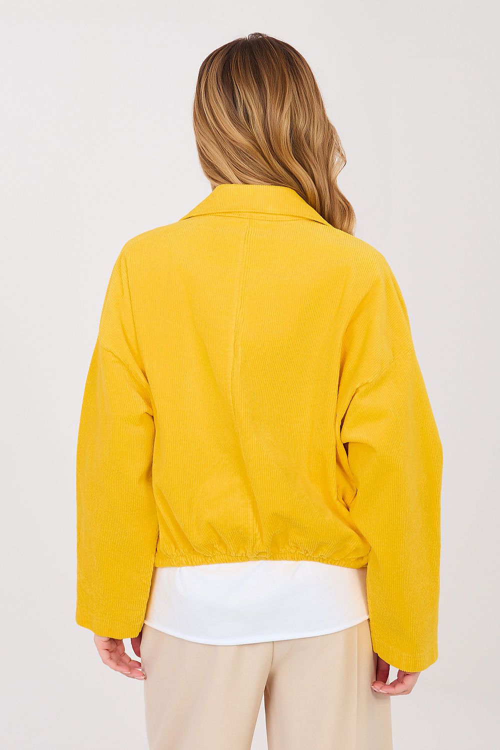 Person wearing a yellow jacket on a plain background