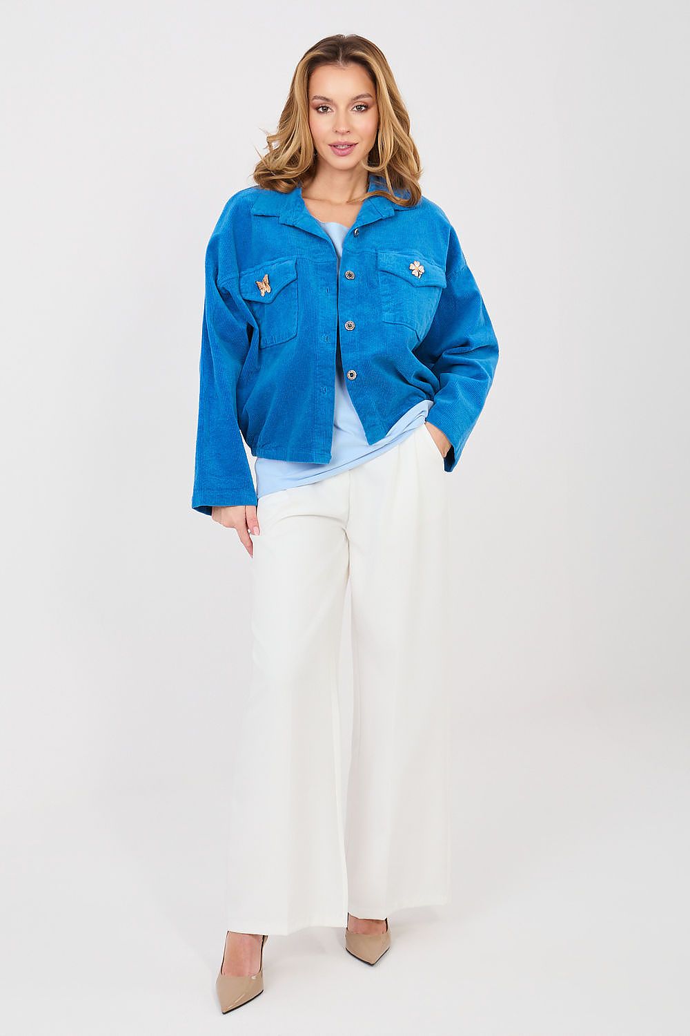 Woman wearing a blue jacket and white pants on a white background