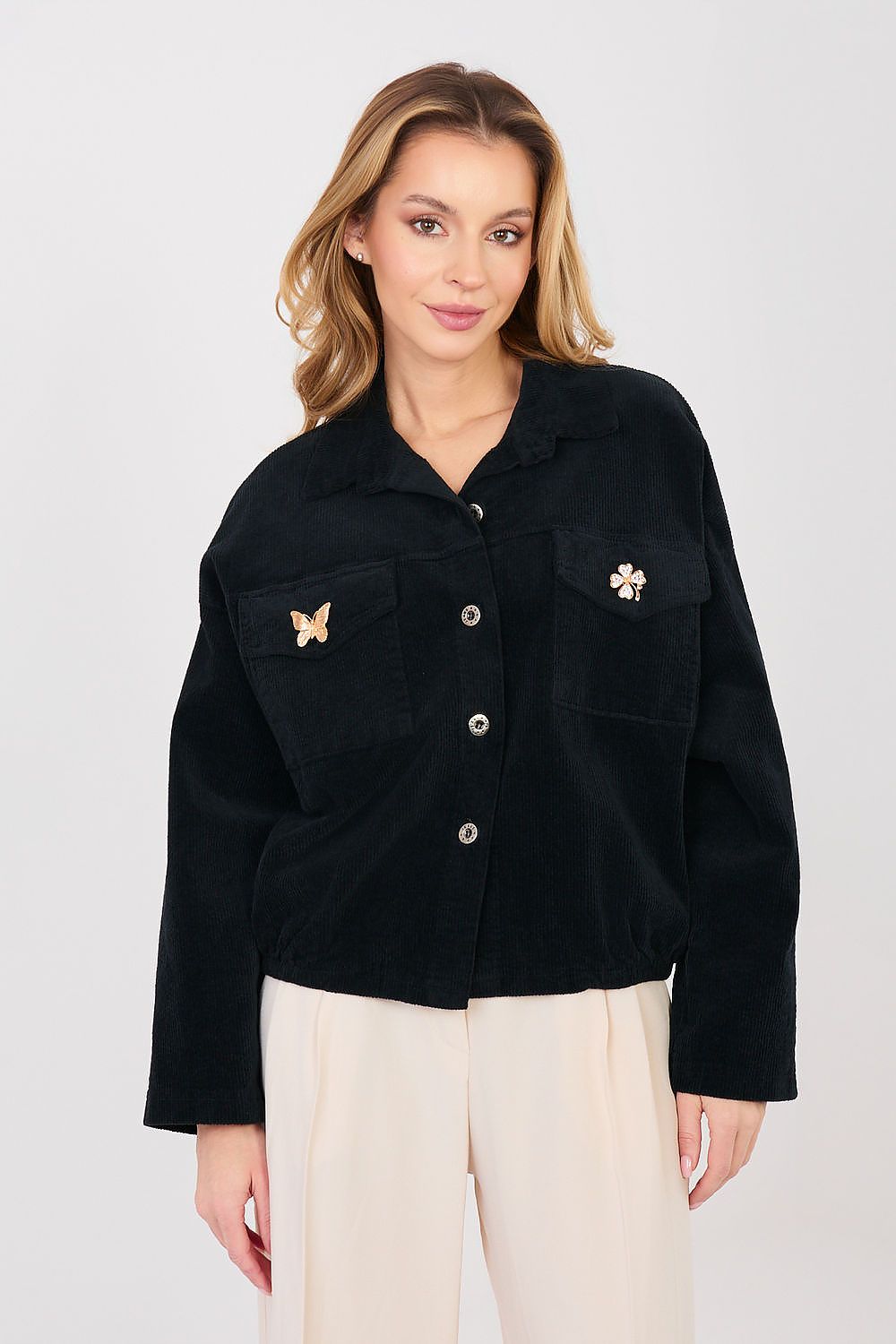 Woman wearing a black jacket with floral buttons on a white background