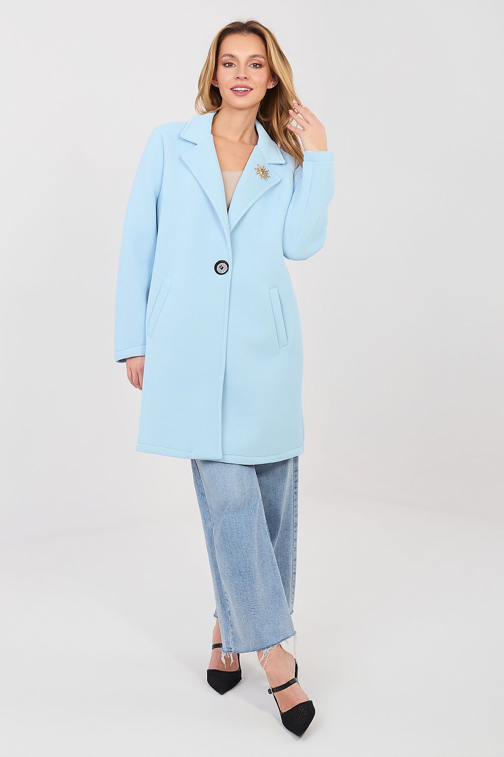 Woman wearing a light blue coat and pants on a white background