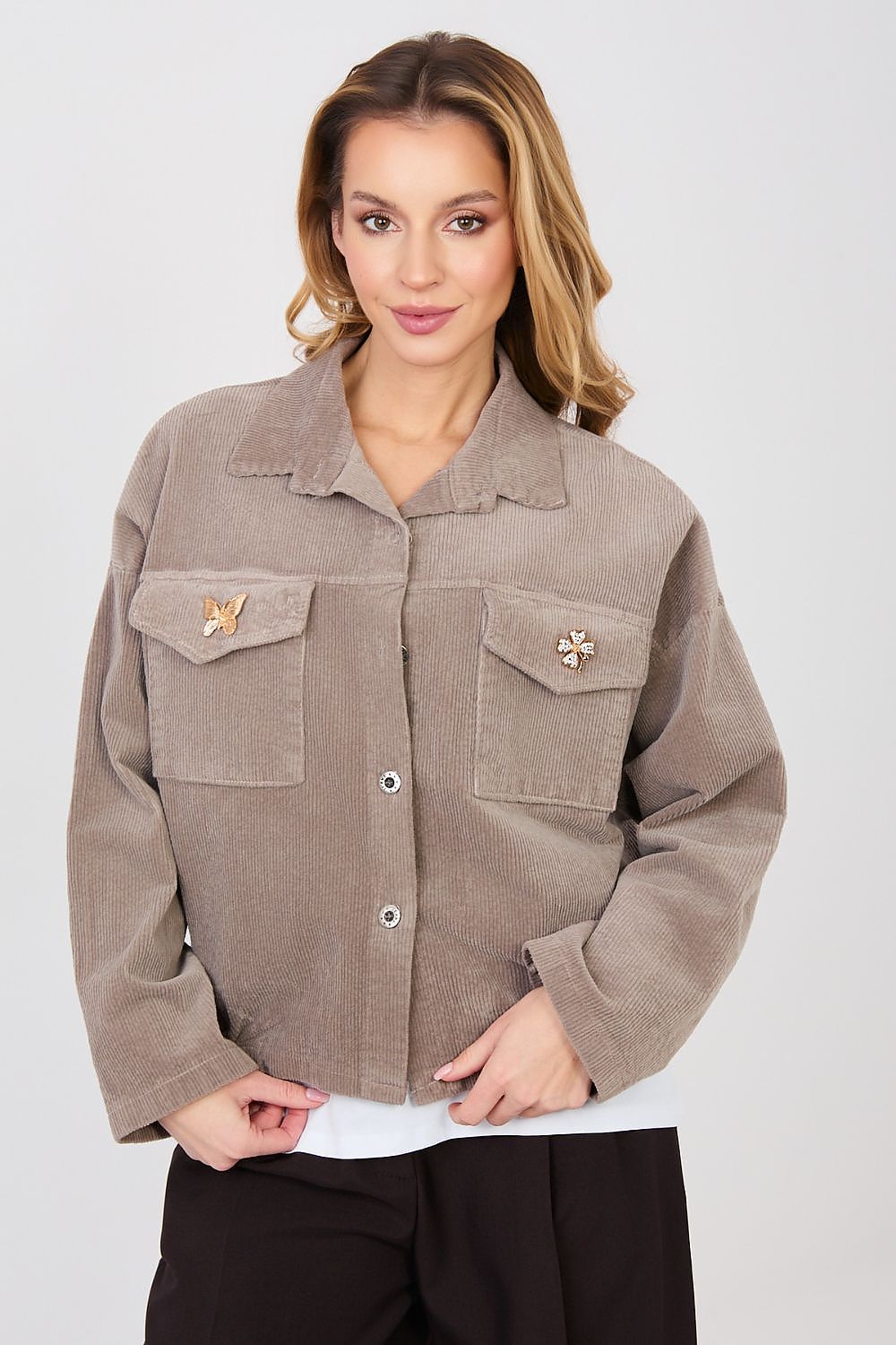 Woman wearing a brown jacket with decorative buttons on a white background