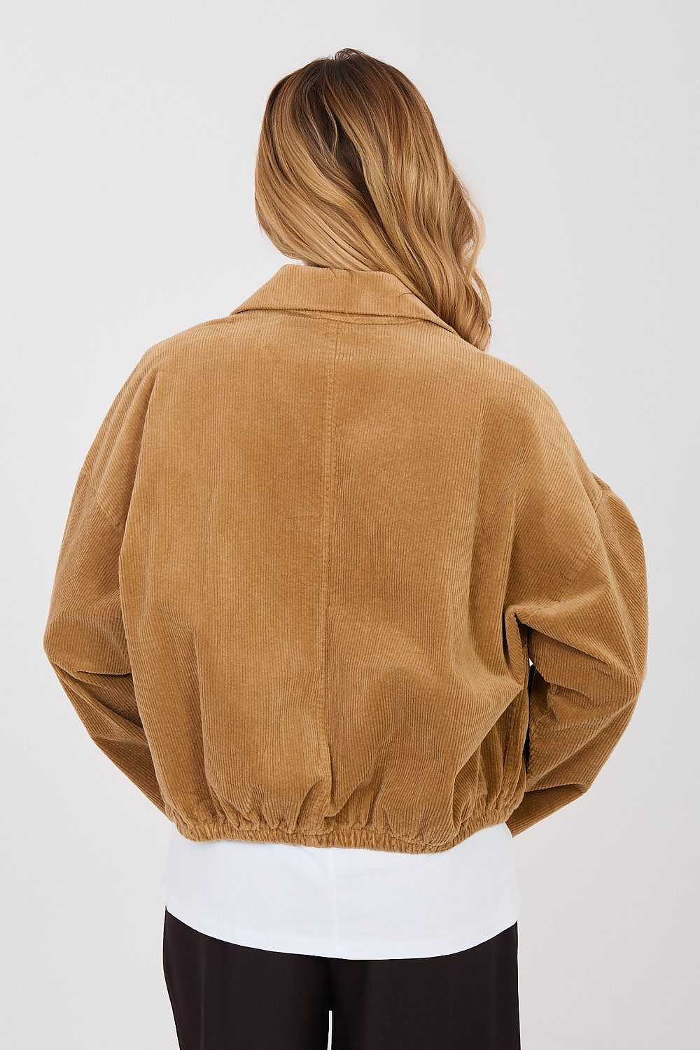 Person wearing a brown jacket on a plain background