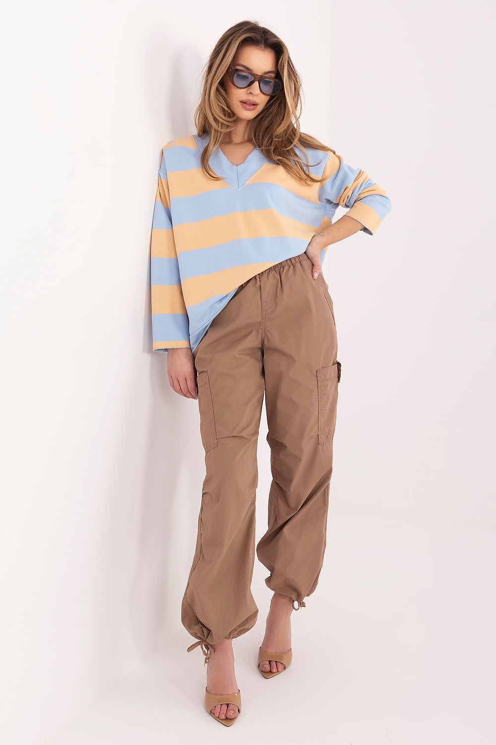 Woman wearing a striped sweater and beige pants on a white background