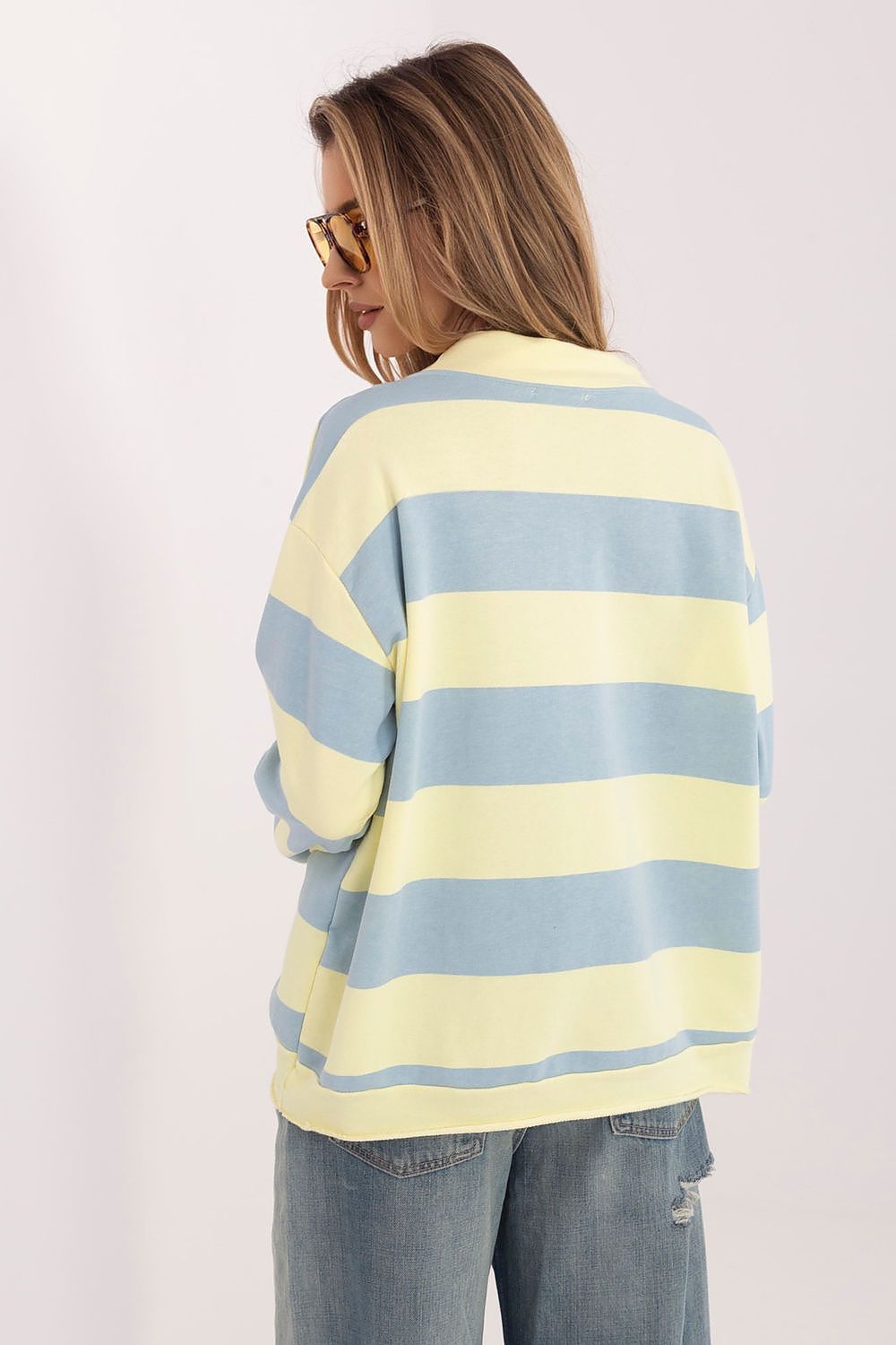 Woman wearing a yellow and blue striped sweater on a white background