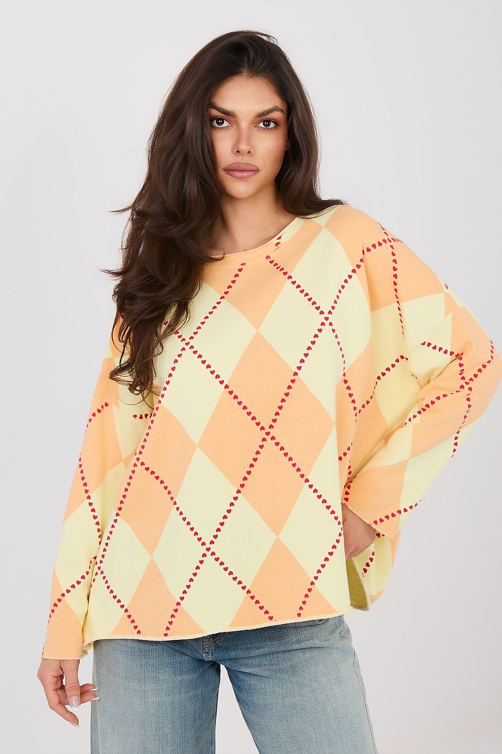 Woman wearing a yellow and orange argyle patterned sweater on a white background