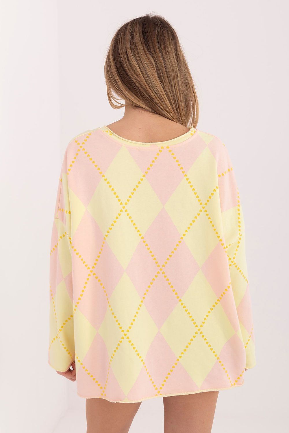 Person wearing a pastel argyle patterned sweater on a white background