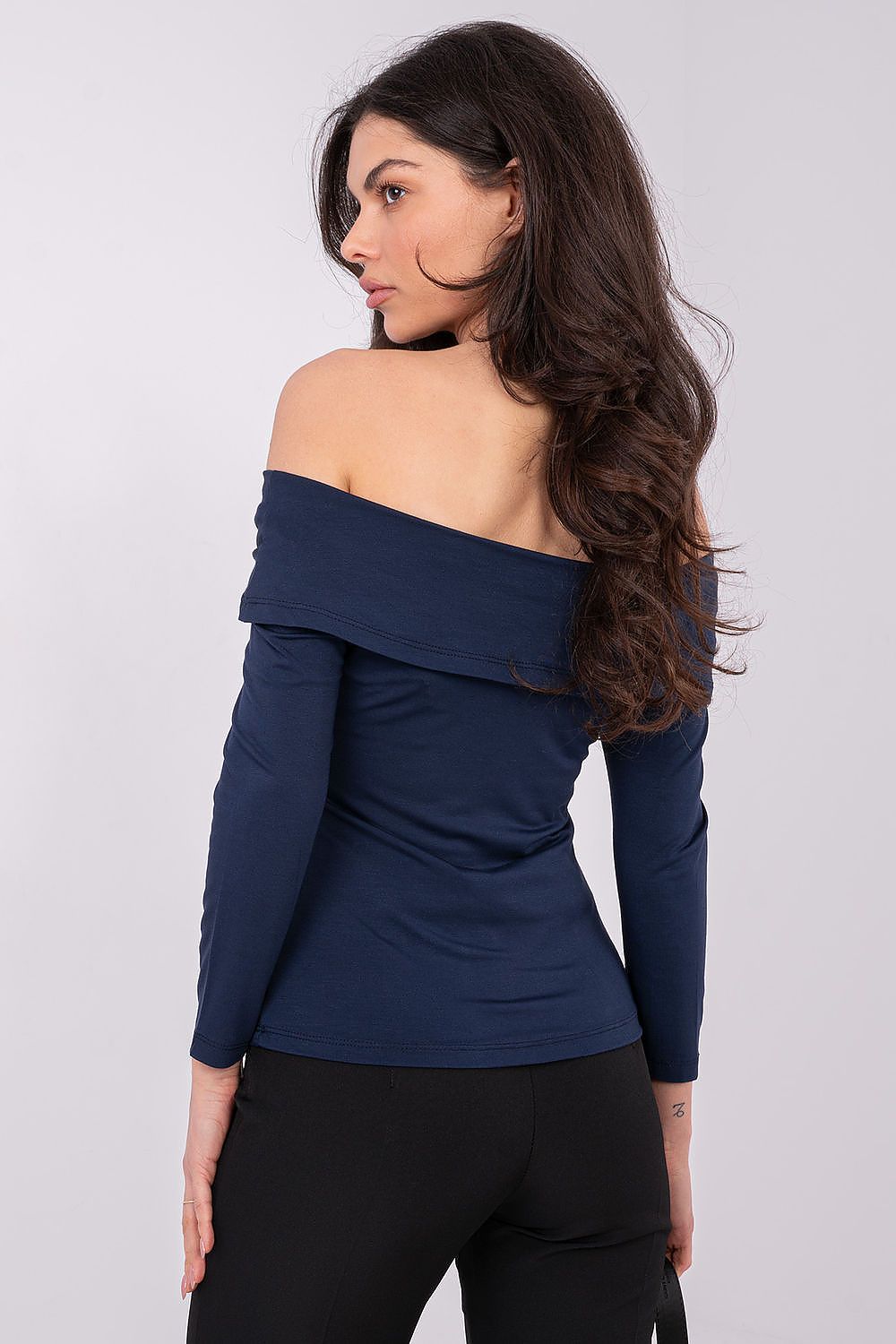 Woman wearing a blue off-shoulder top and black pants on a white background