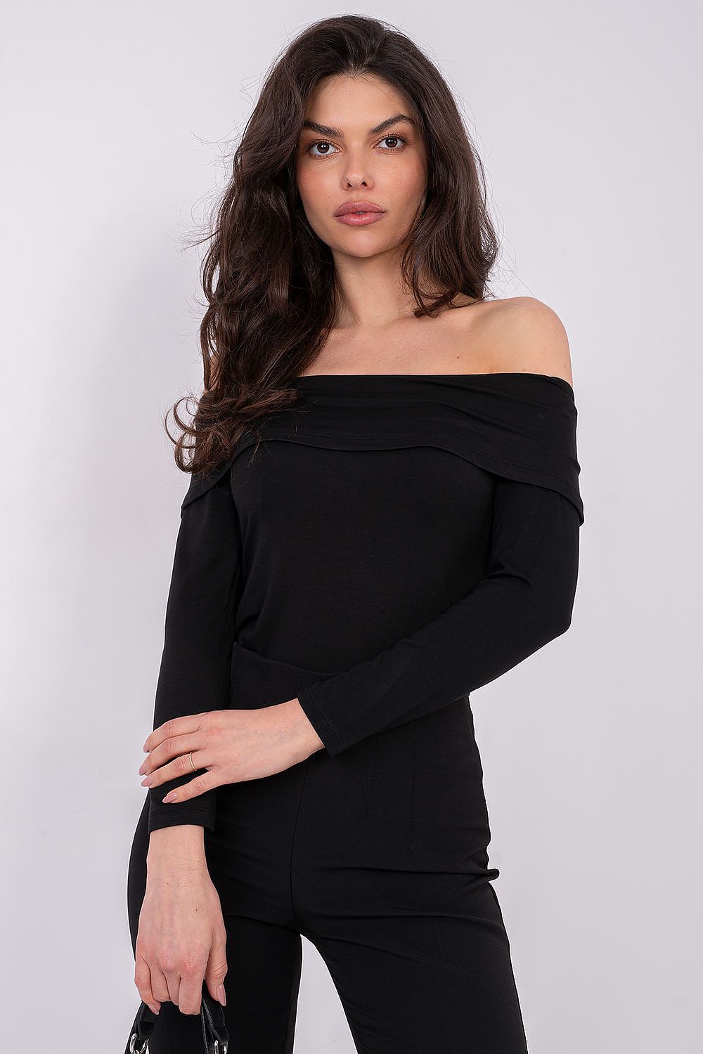 Woman wearing a black off-shoulder top against a white background