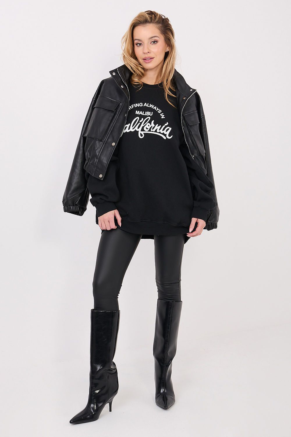 Woman wearing a black leather jacket, black hoodie with text, and black leather pants on a white background